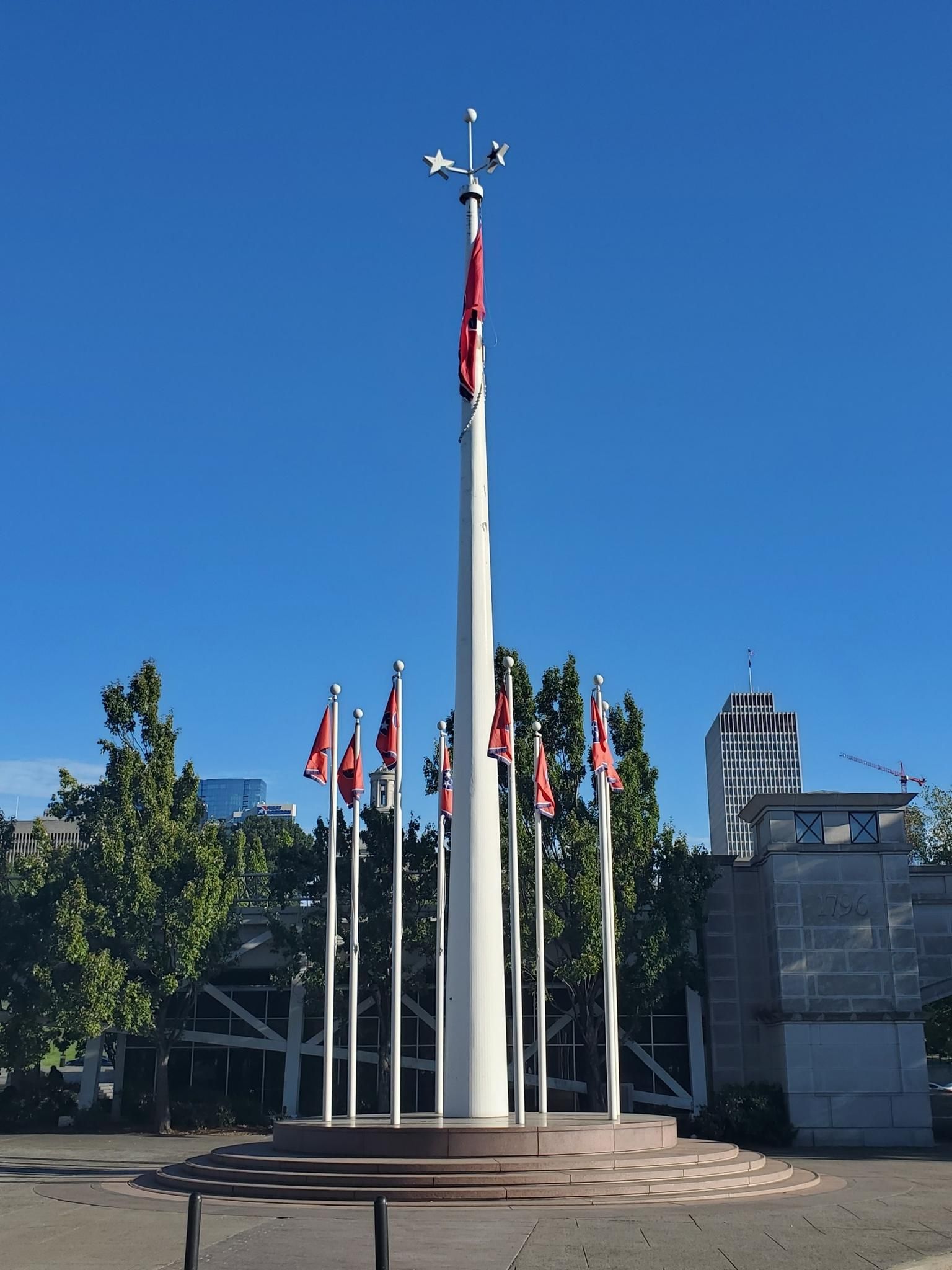 A tall flagpole with a large flag, surrounded by smaller flags on a clear day. - Cumberland River Greenway and Bicentennial Mall Loop