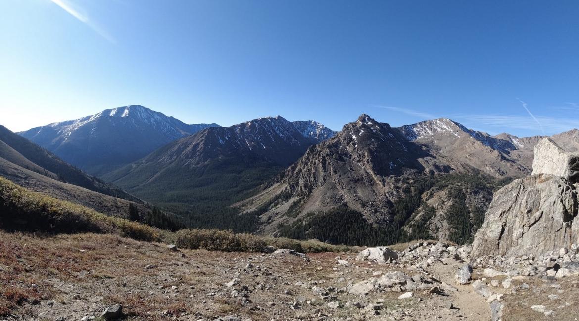 Panoramic view of rugged mountains with snow-capped peaks under a clear blue sky.