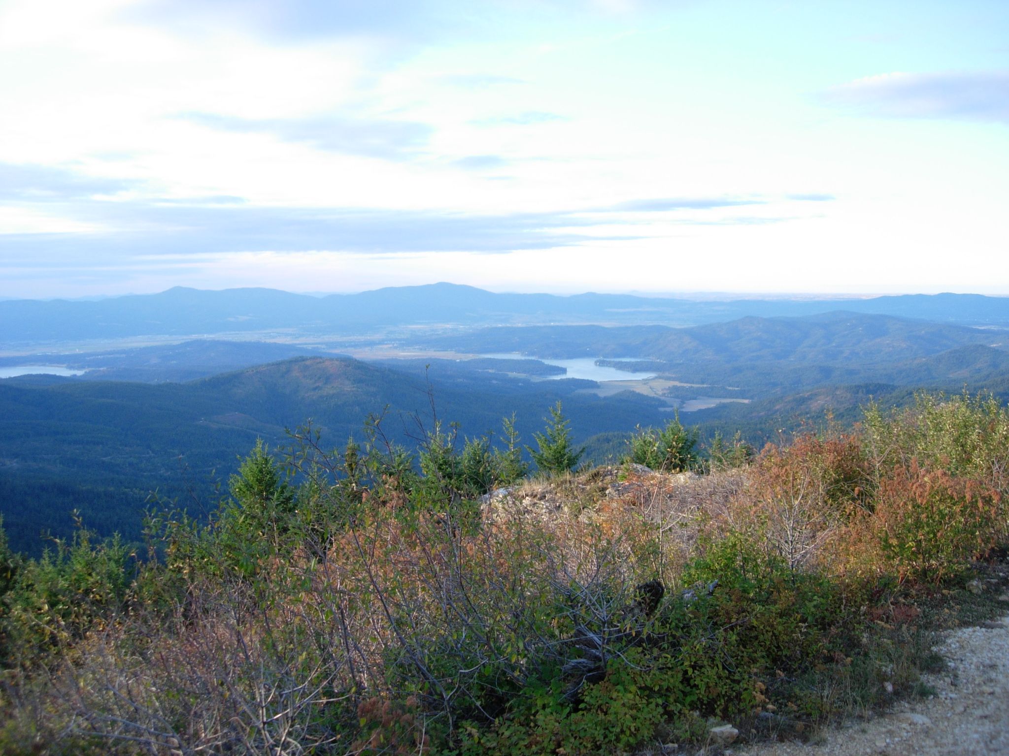 Expansive view of forested mountains, a distant lake, and cloudy sky. - Quartz Mountain Fire Lookout Trail