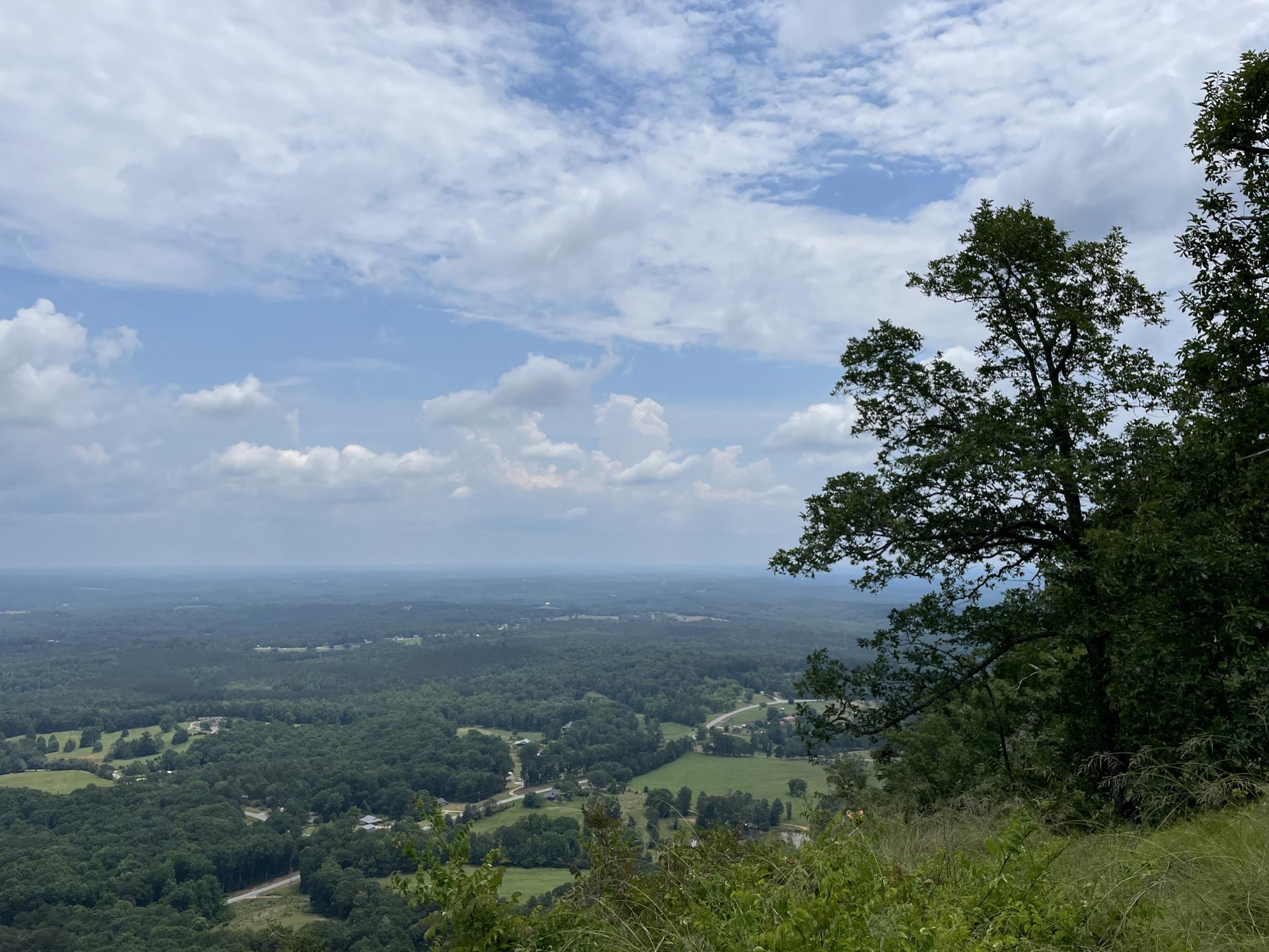 Panoramic view of a lush green valley under a partly cloudy sky.