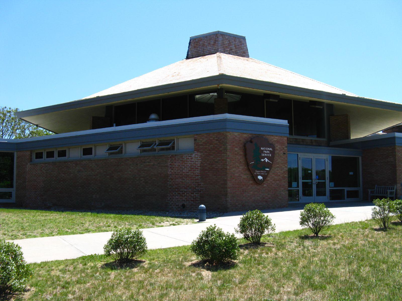Brick building with a large, distinctive roof under a clear blue sky.