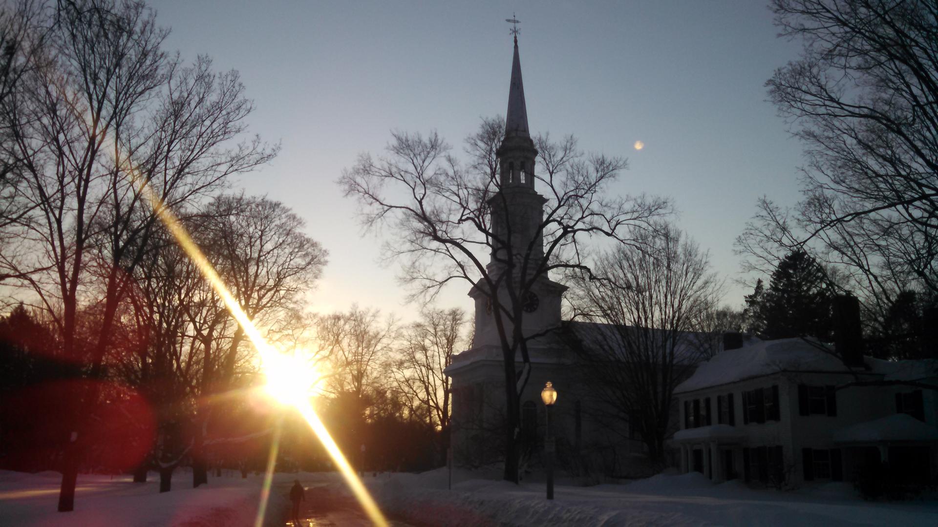 Church steeple silhouetted against a golden winter sunset with snow.
