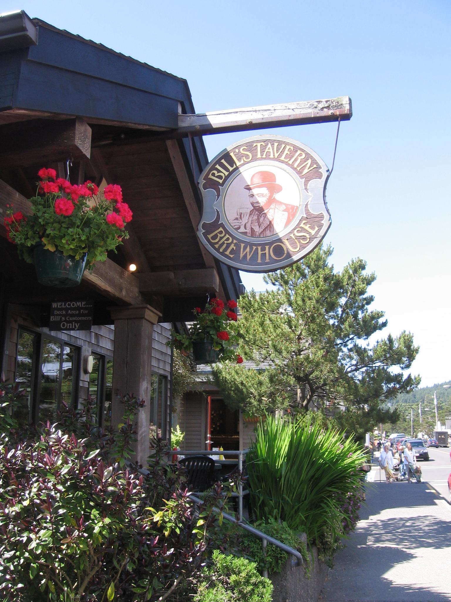 Sunny view of a building with a 'Tavern Brewhouse' sign and flowers.