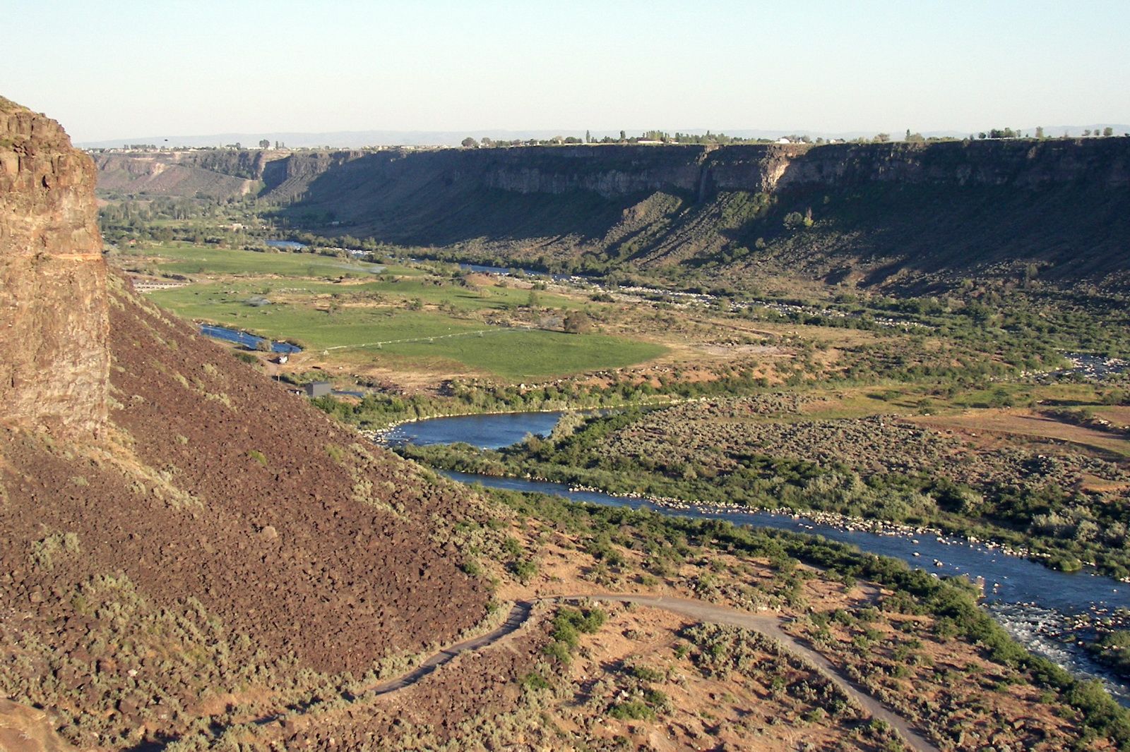 River flows through a wide canyon with green fields and arid slopes in daylight. - Auger Falls Park loop