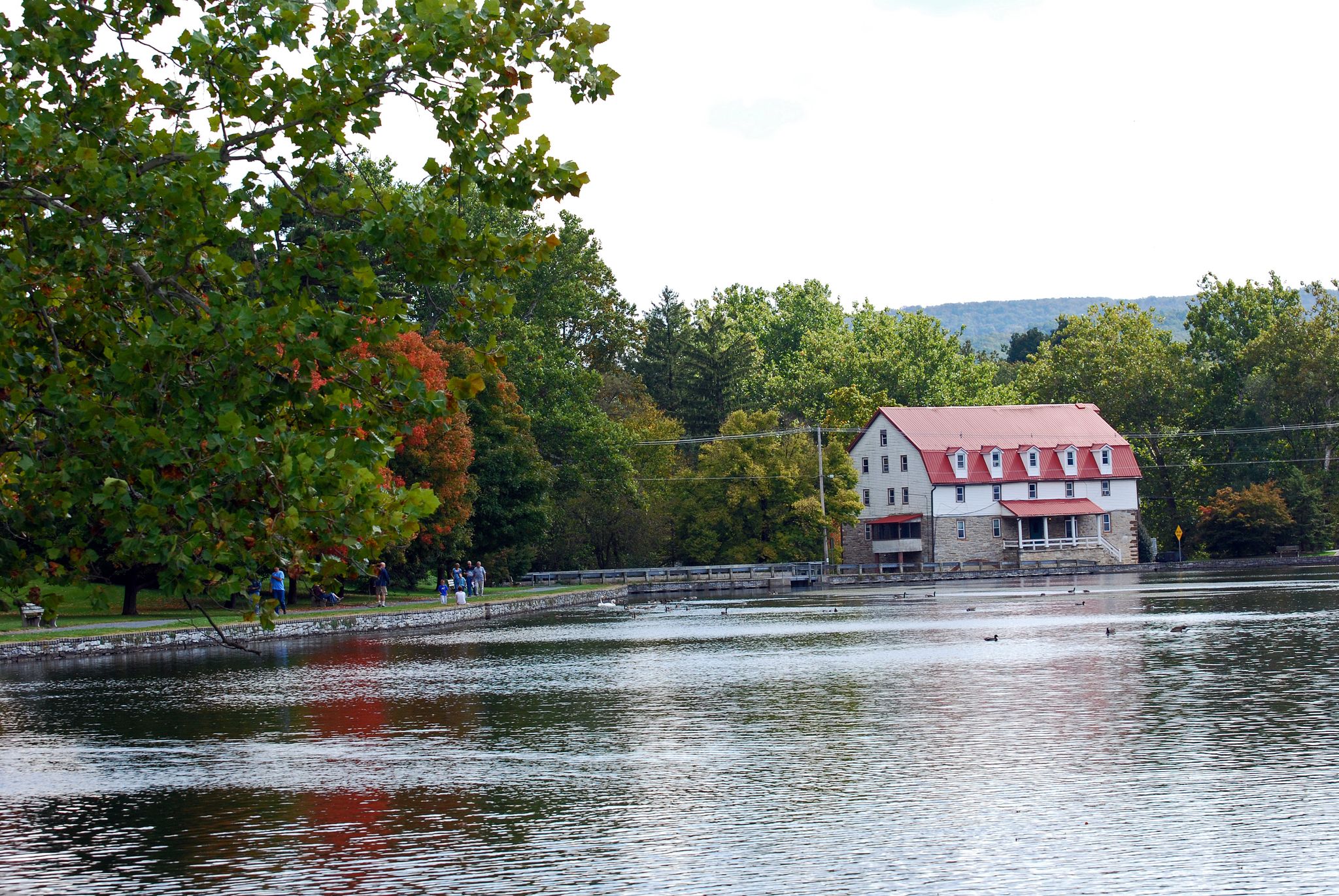 A large building with a red roof by a lake, people walking on a path. - Children's Lake loop from Appalachian Trail Parking