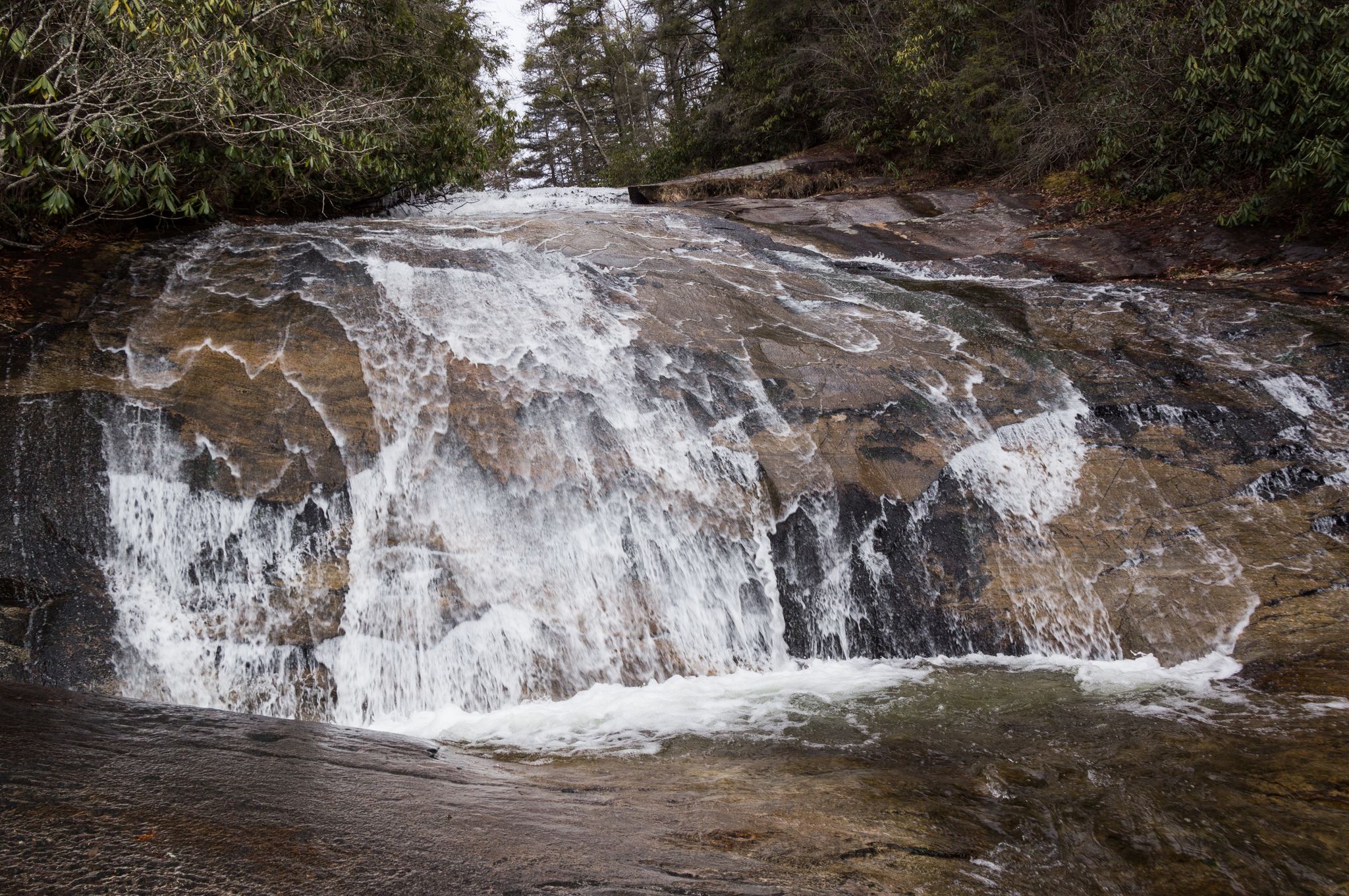 Waterfall cascades over dark, wet rocks with trees in the background. - Sandy Trail & Wintergreen Falls loop