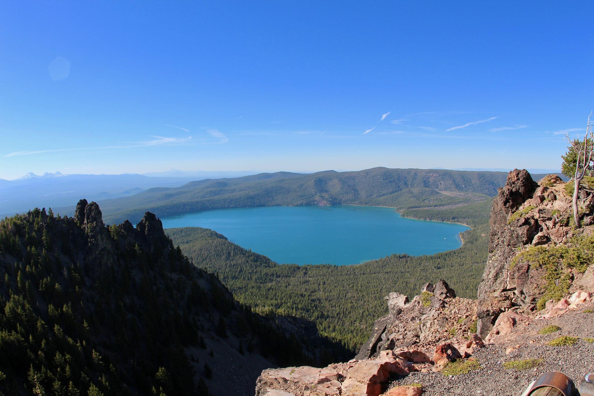 Vibrant blue lake surrounded by green forests and rocky mountains.