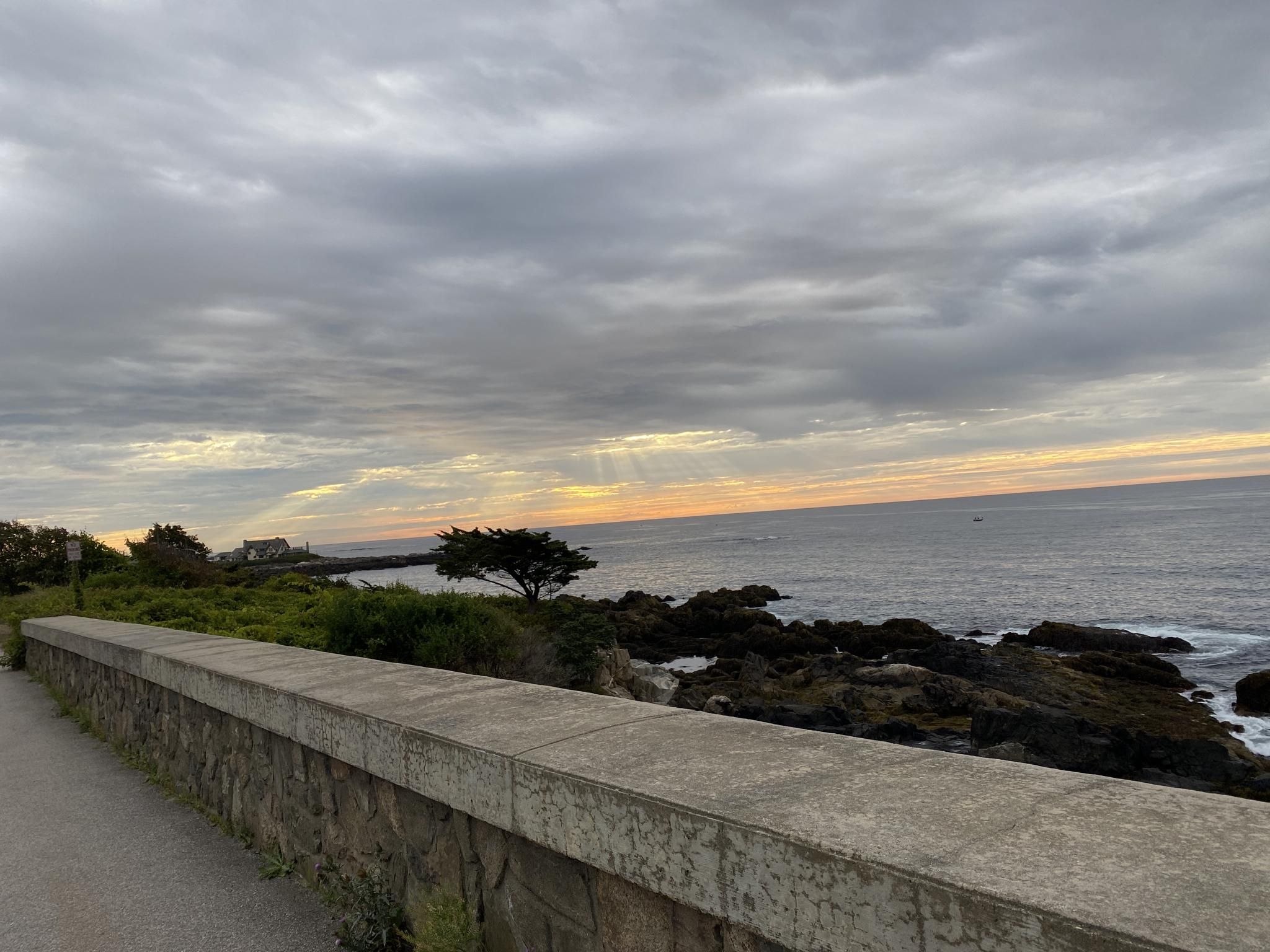 Cloudy sunset over a rocky coastline, viewed from a stone wall. - Parson's Way and Walker's Point Loop