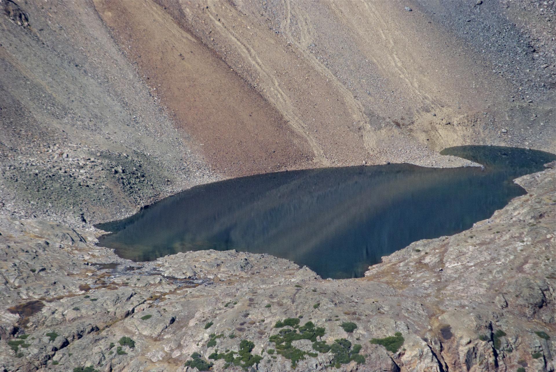 Dark alpine lake nestled in a steep, rocky mountain basin.