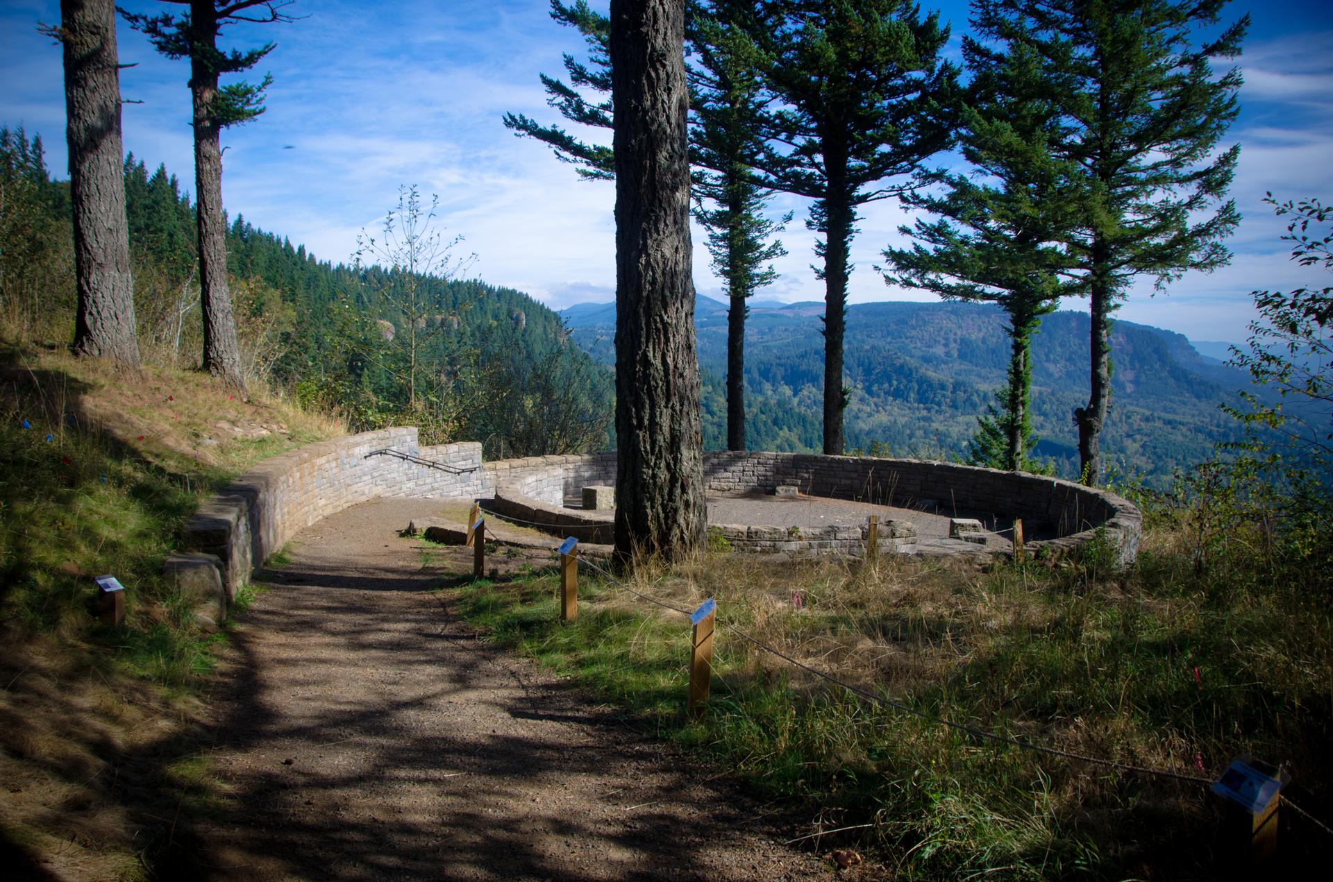 Stone overlook structure on a forested hill with a dirt path.