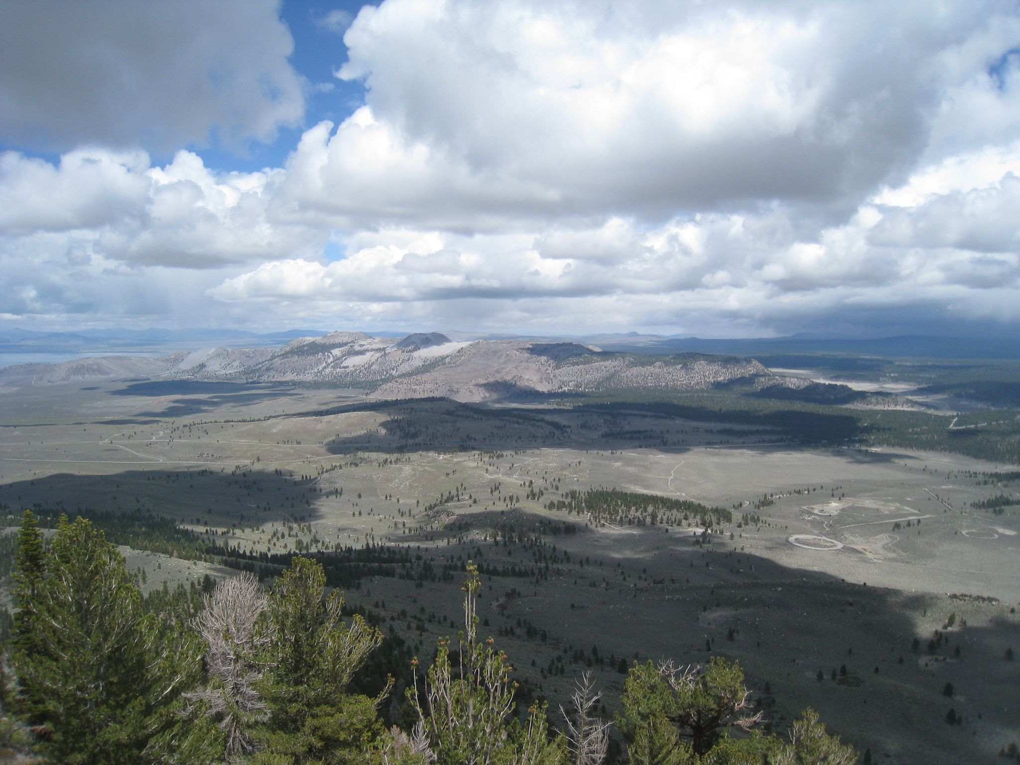 Expansive mountain valley under a cloudy sky with sunlit and shadowed areas. - Reversed Peak Trail