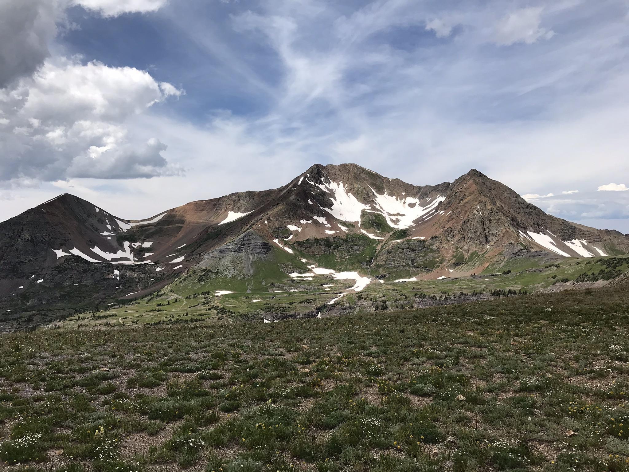 Vast mountain range with snow patches under a partly cloudy sky.
