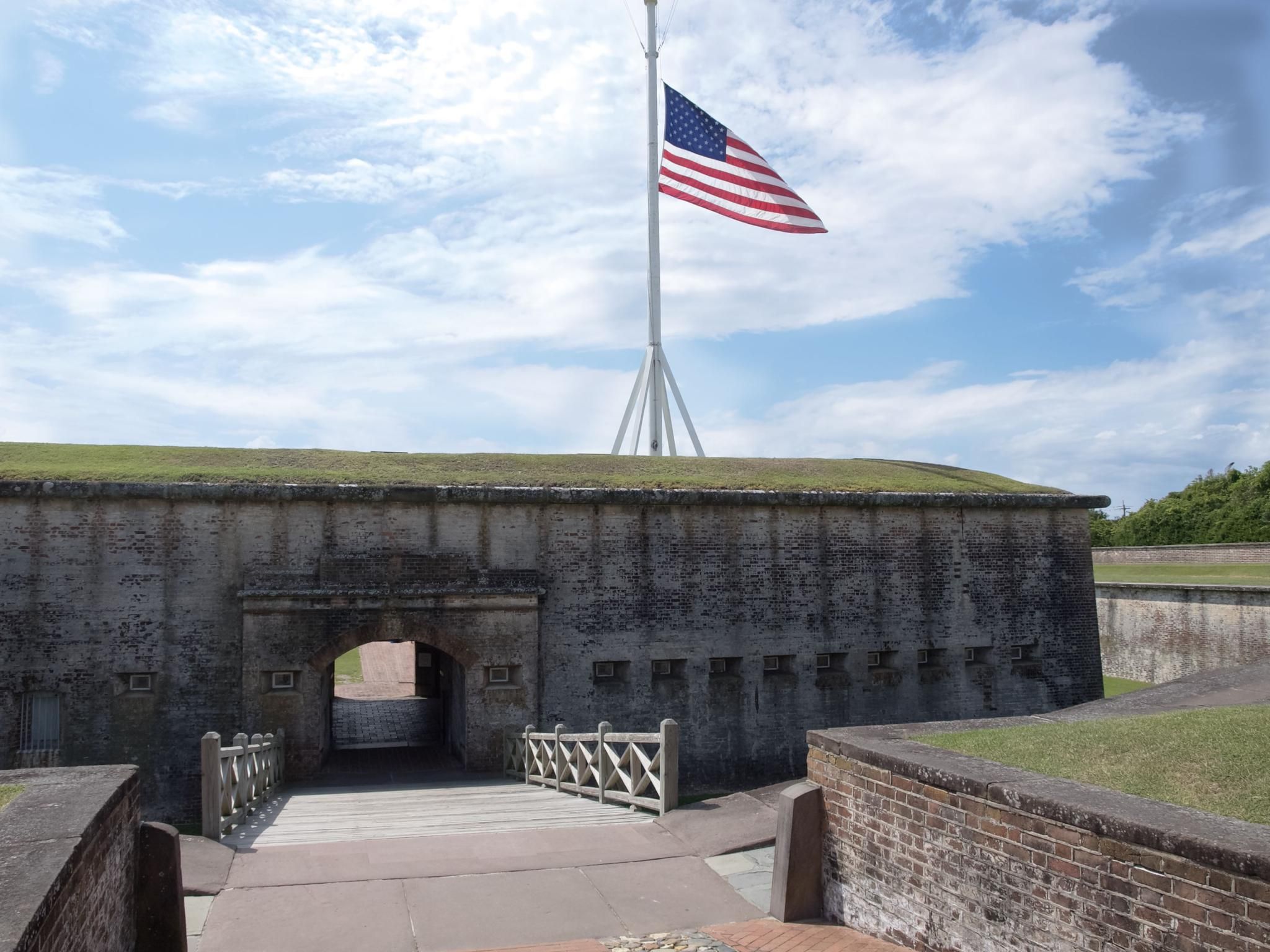 An American flag flies above a historic stone fort entrance on a sunny day. - Elliott Coues Nature Trail