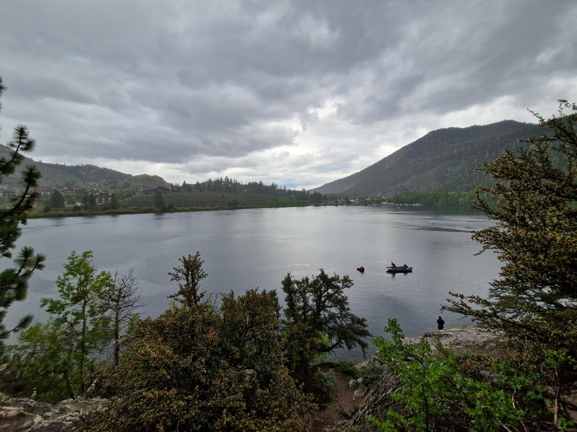 Overcast sky above a lake with a boat and distant mountains.