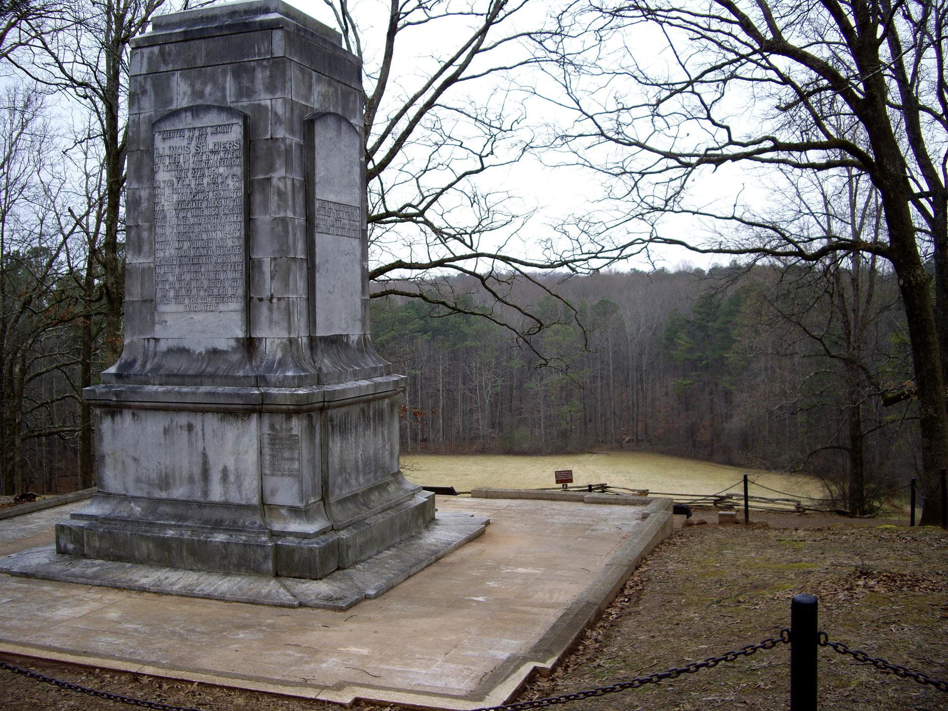 Large stone monument overlooking a grassy clearing and bare winter trees.