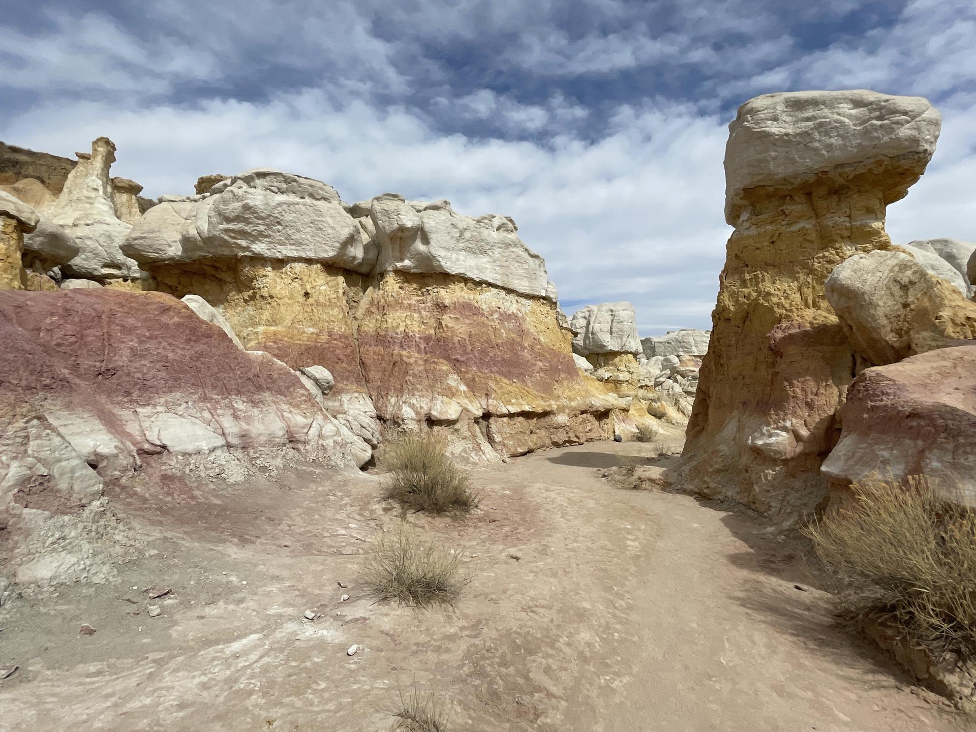 A narrow path winding through colorful, layered rock formations.