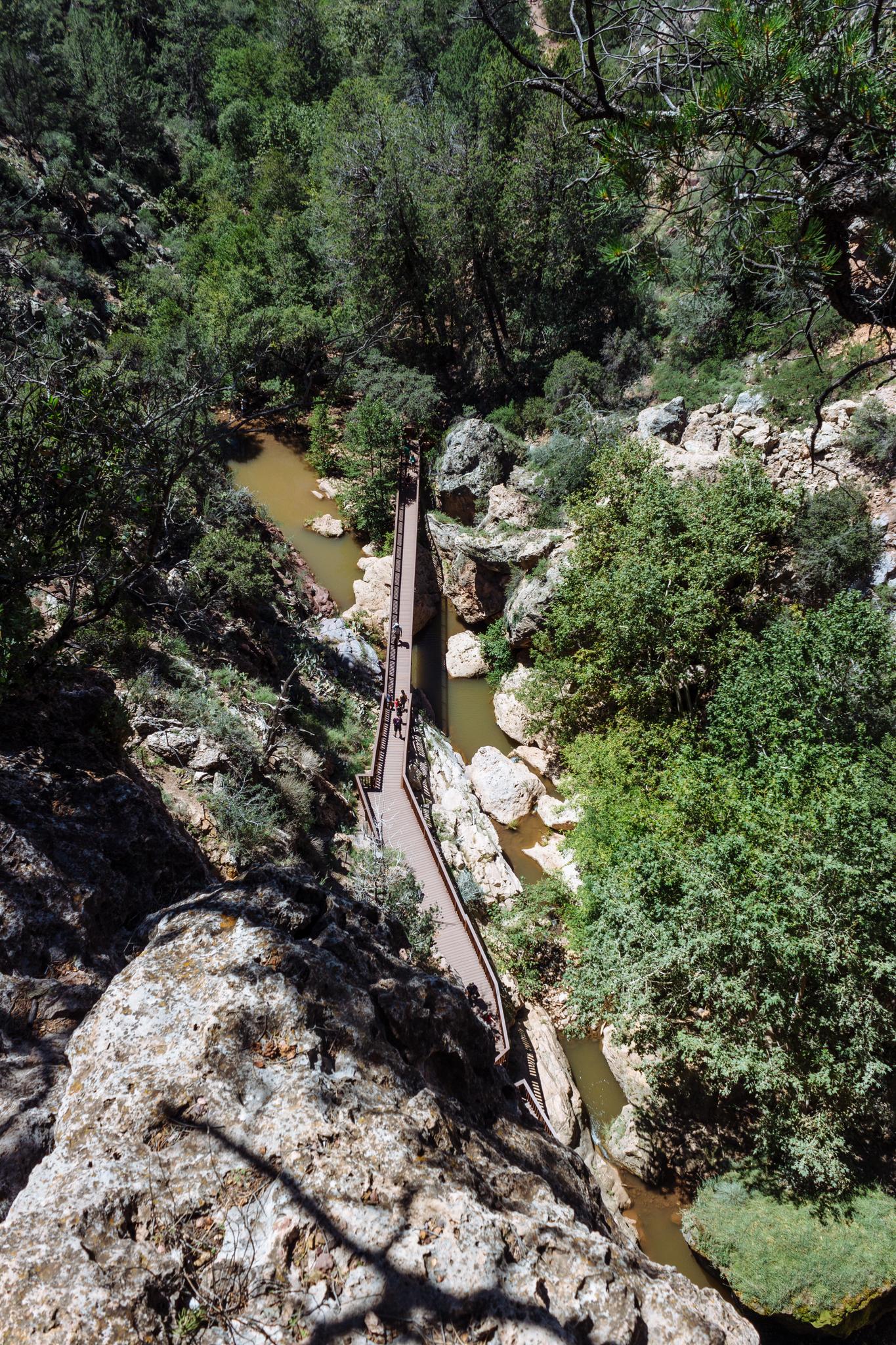 Overhead view of a long bridge spanning a rocky river canyon.