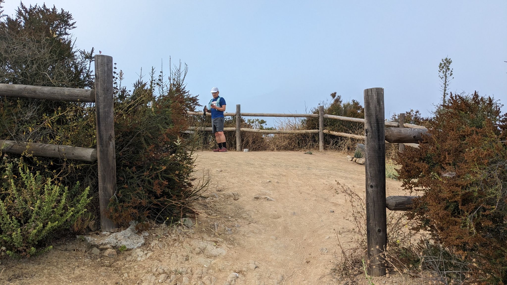 Man standing by a wooden fence on a hilltop, clear sky. - Space Mountain and Rosewood Trail Loop