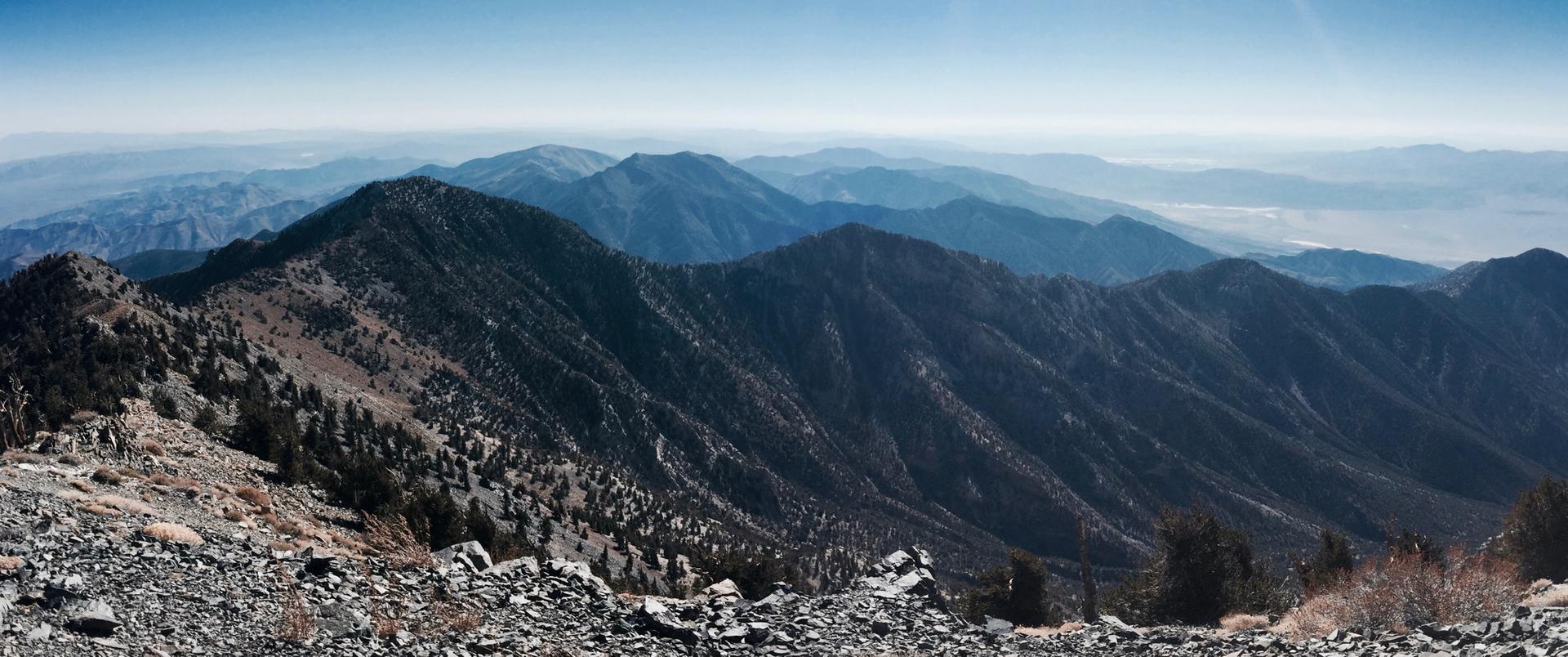 Panoramic view of rugged mountains under a bright, clear sky.