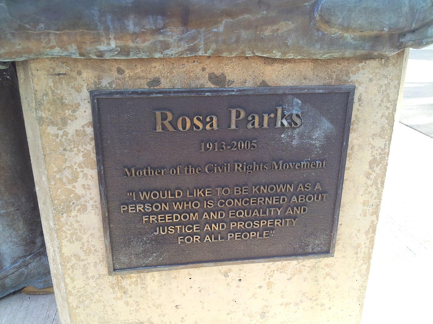 Close-up of a bronze plaque dedicated to Rosa Parks on a stone base.