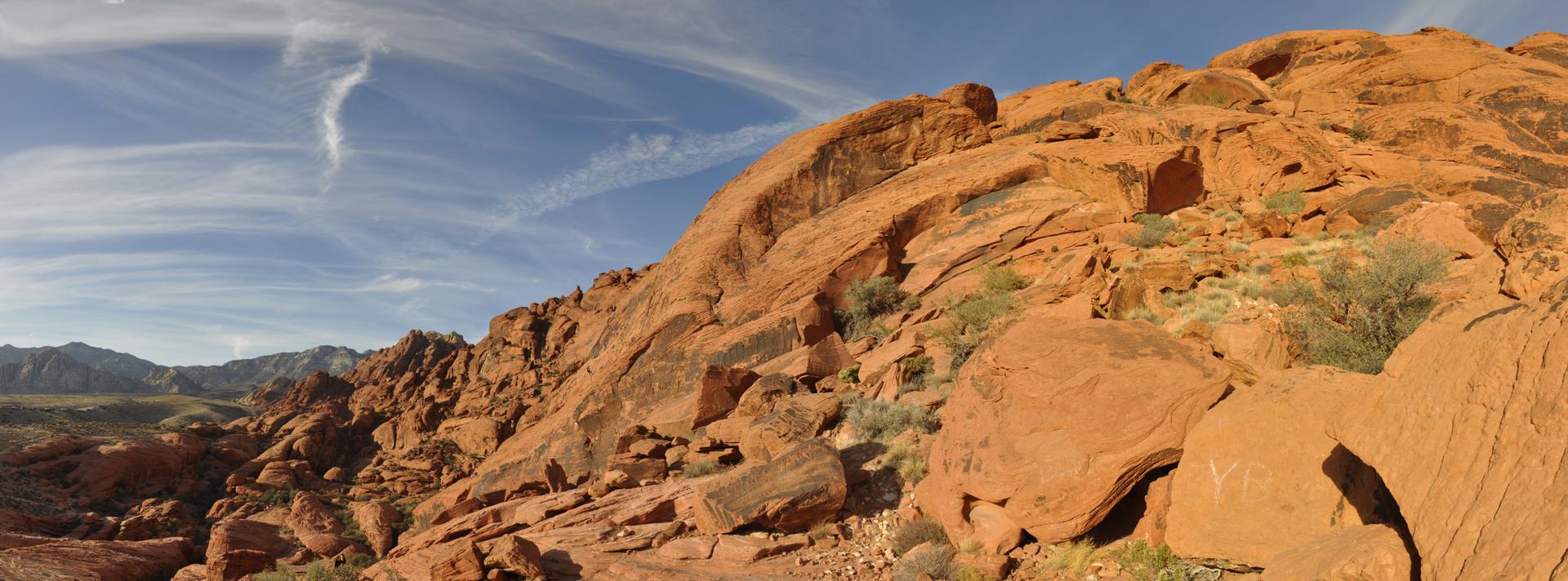 Panoramic view of vibrant red rock hills under a bright blue sky.