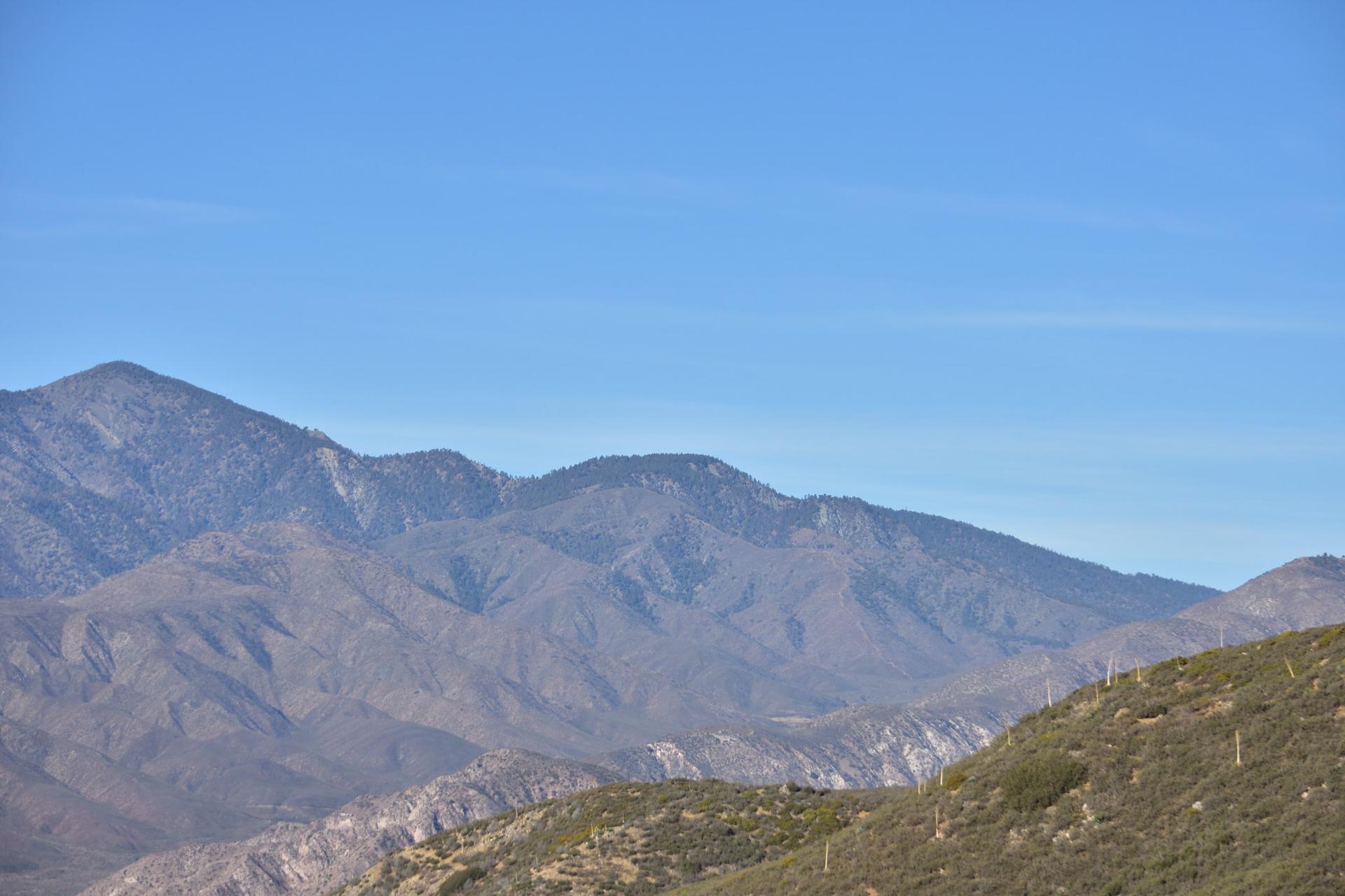 Wide view of arid mountain range under a clear blue sky.