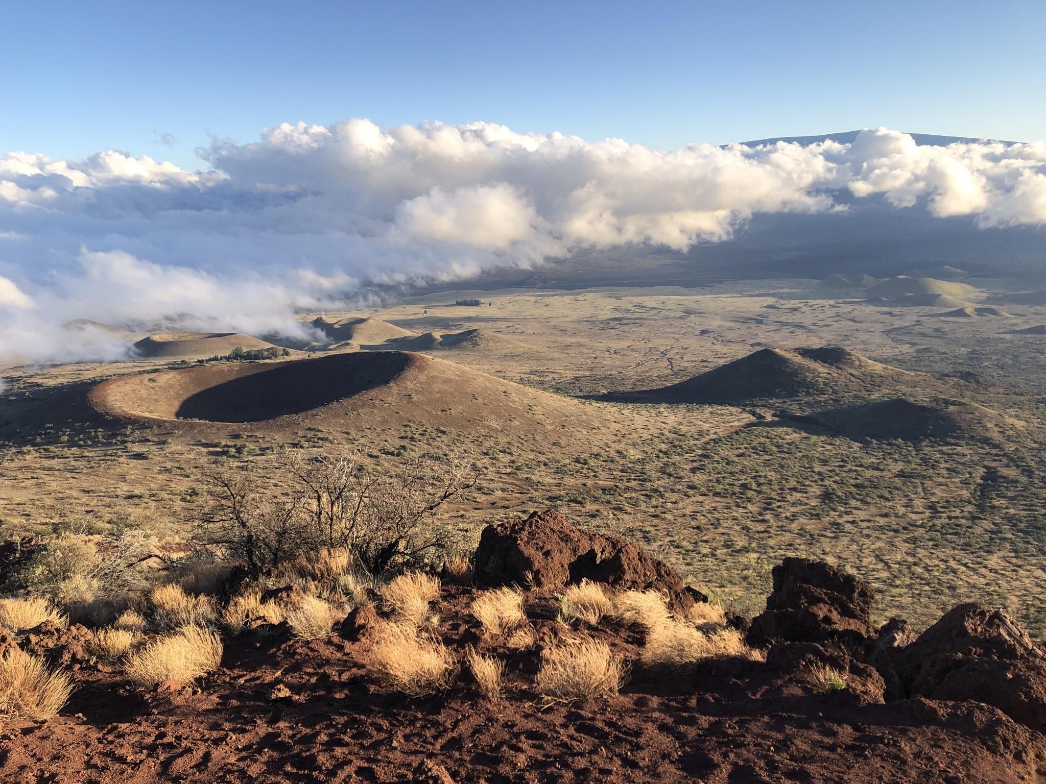 Aerial view of volcanic craters and dry landscape under a cloudy sky. - Pu‘ukalepeamoa Lookout