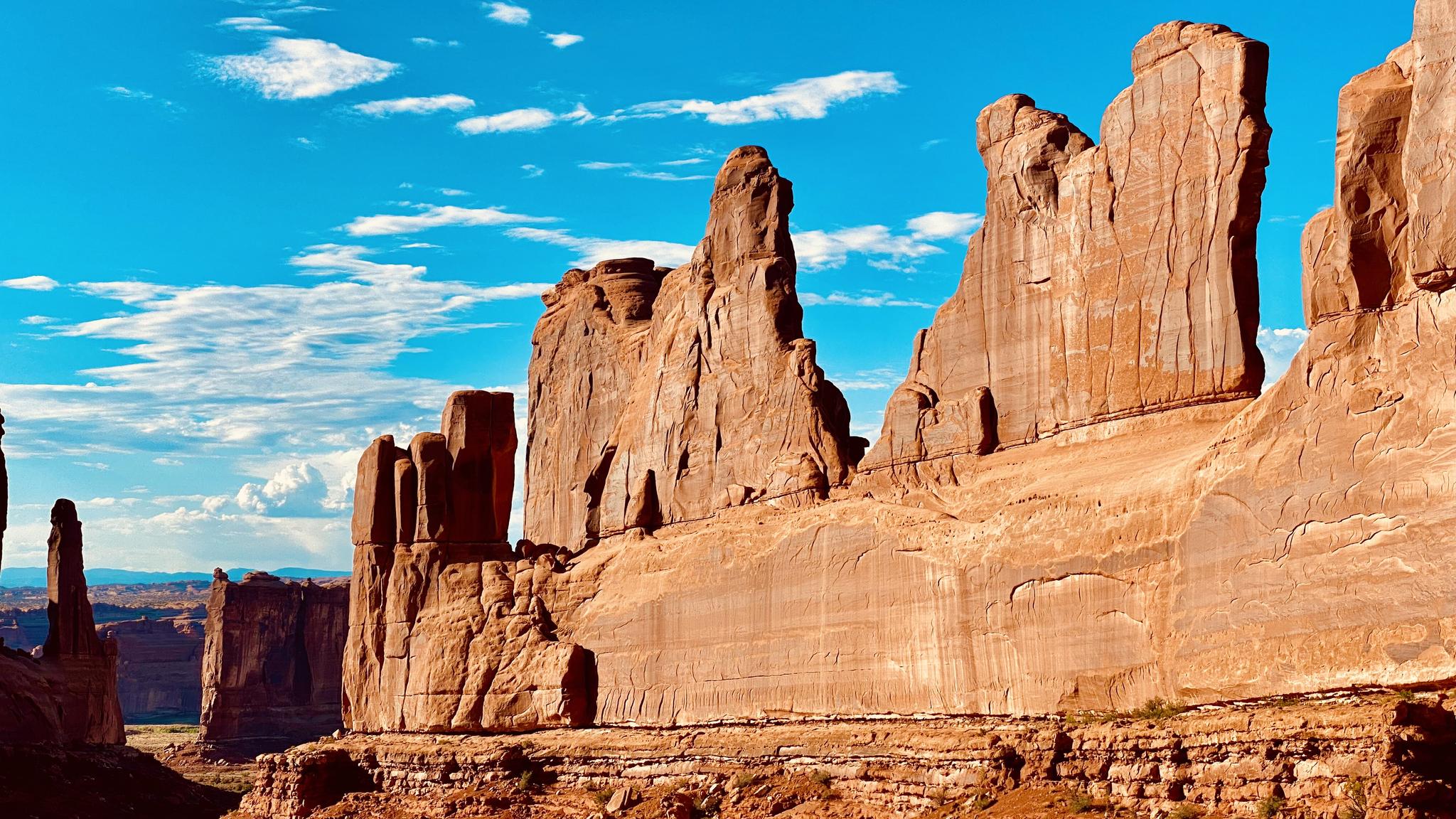 Towering red rock formations under a vibrant blue sky with white clouds.