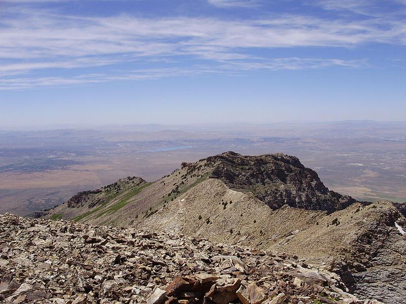 Rocky mountain peak with vast plains stretching to the horizon.
