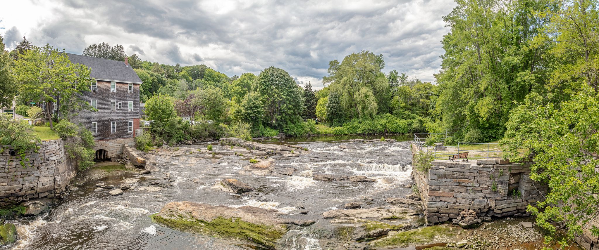 Panoramic view of a wide, rocky river with rapids and an old mill building. - Cabin at Royal River Park – Royal River Park loop from Yarmouth