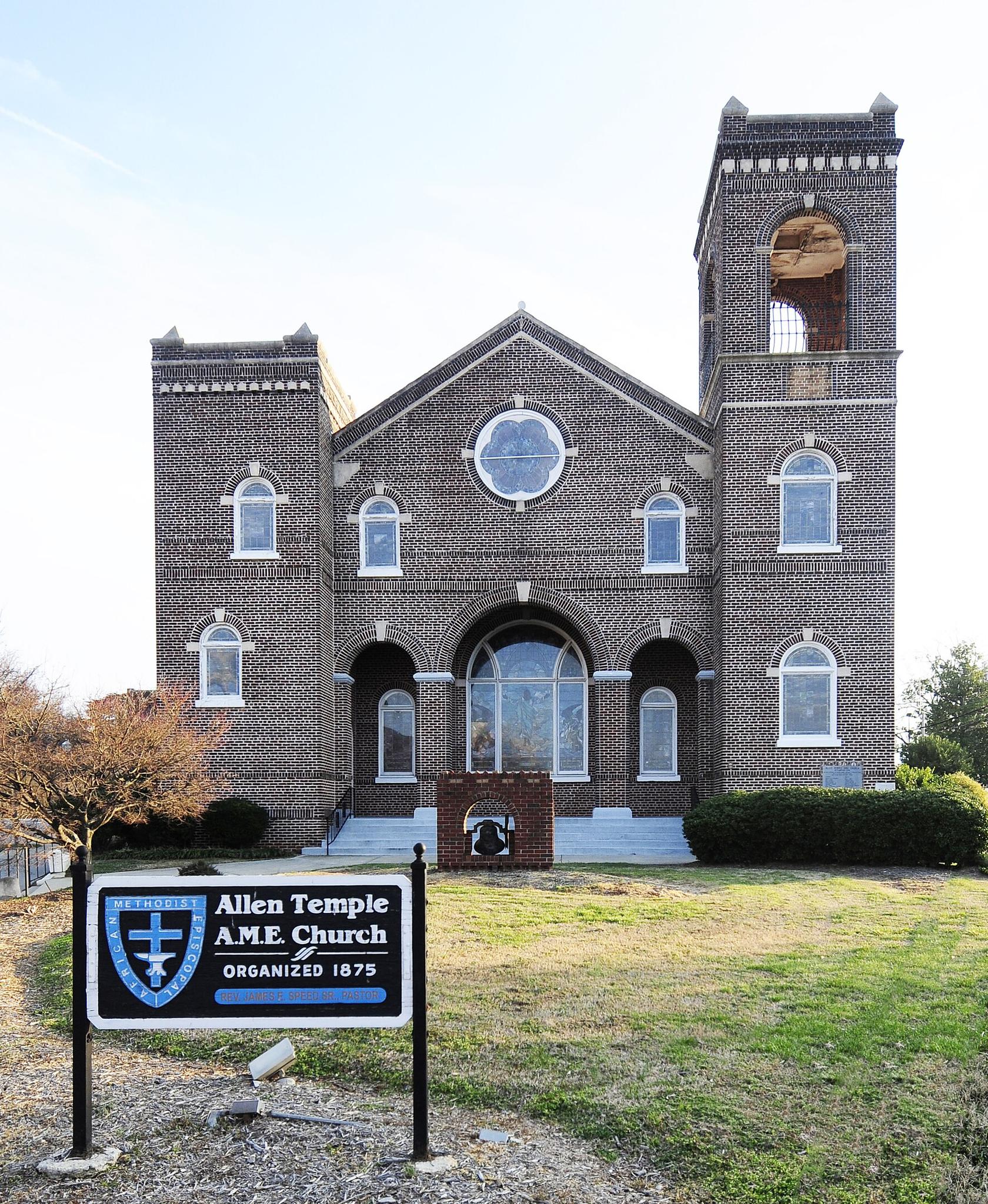 Large brick church with two towers and a round window under a clear sky.