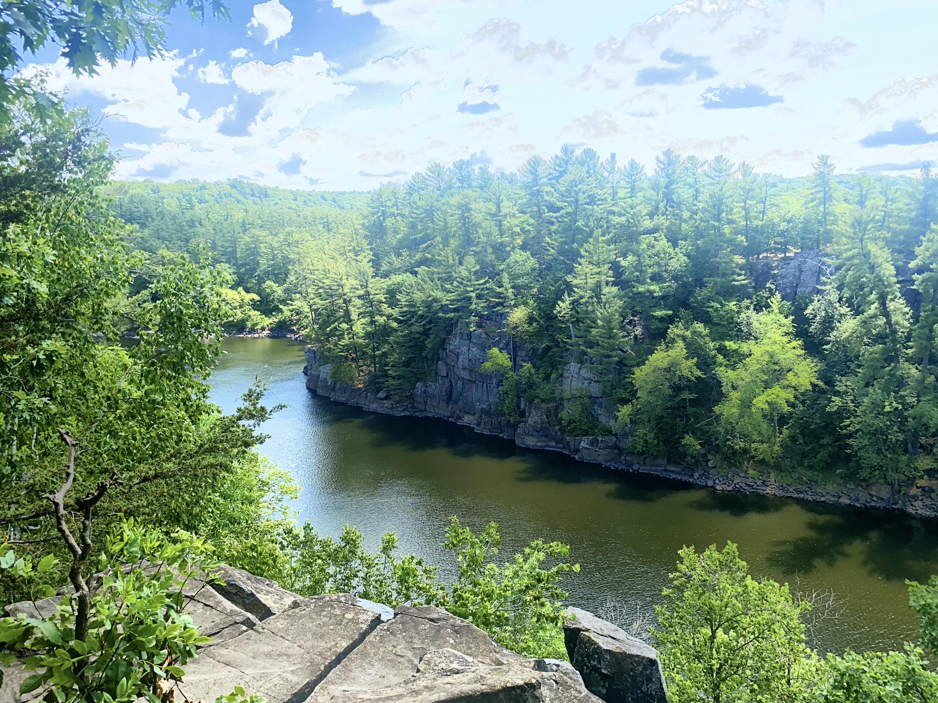 River flowing between steep, green forested cliffs under a bright sky.