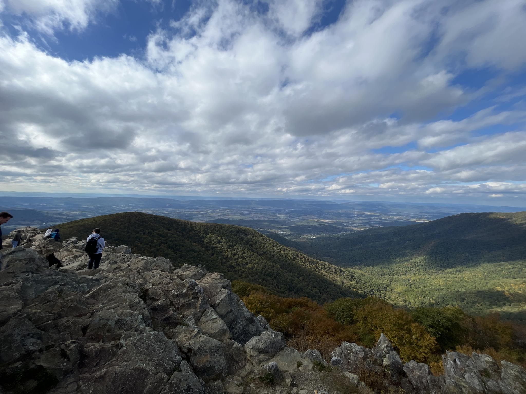 Hikers on a rocky mountain peak overlooking a vast valley. - Upper Hawksbill Trail
