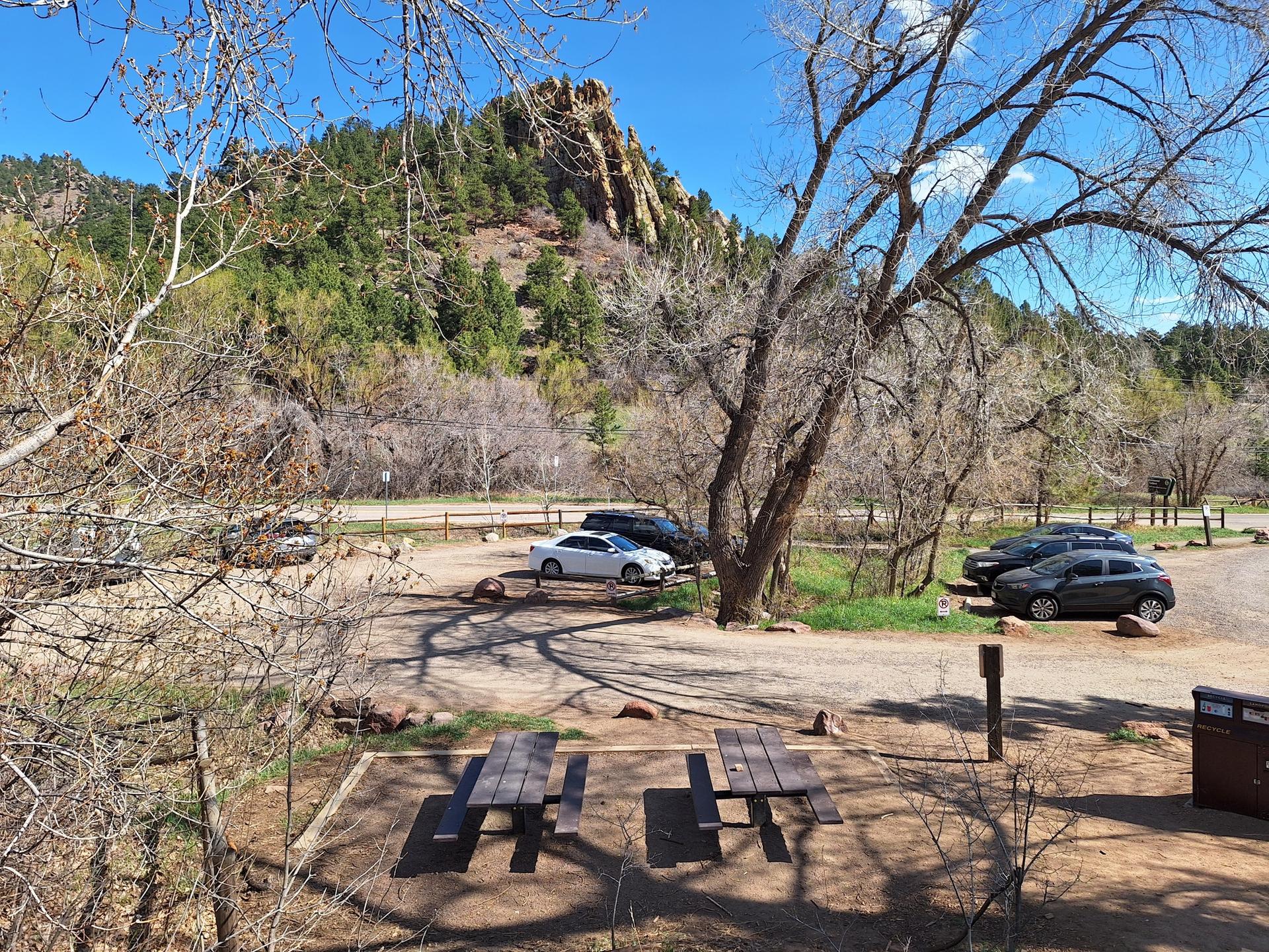 Picnic tables and cars in a parking area near mountains.