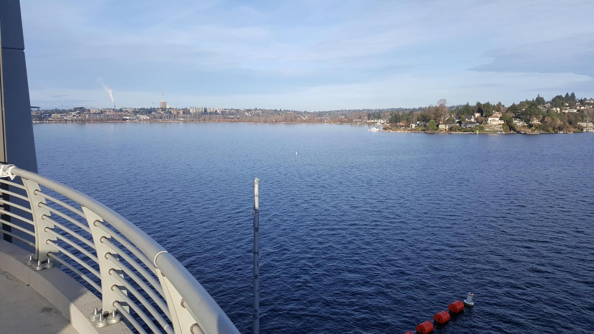 Wide view of a large lake with a distant city under a clear sky.