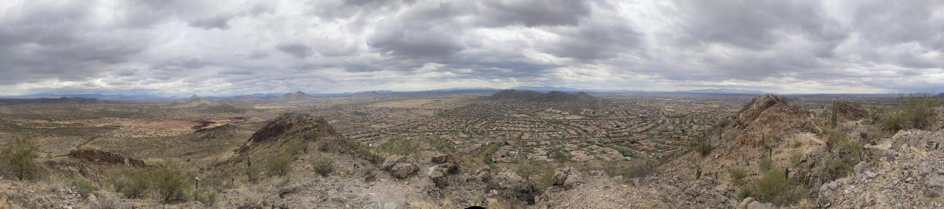 Panoramic view of a vast, rocky desert landscape under an overcast sky.