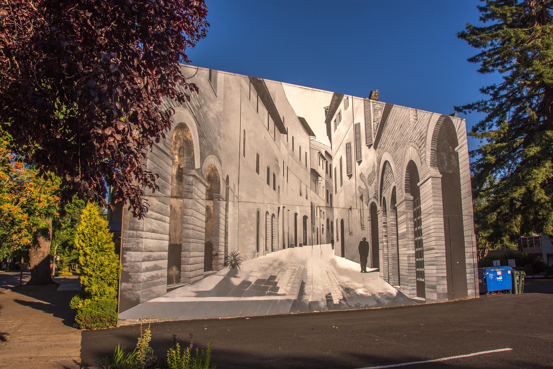 A large mural of an old European street scene on a building wall.