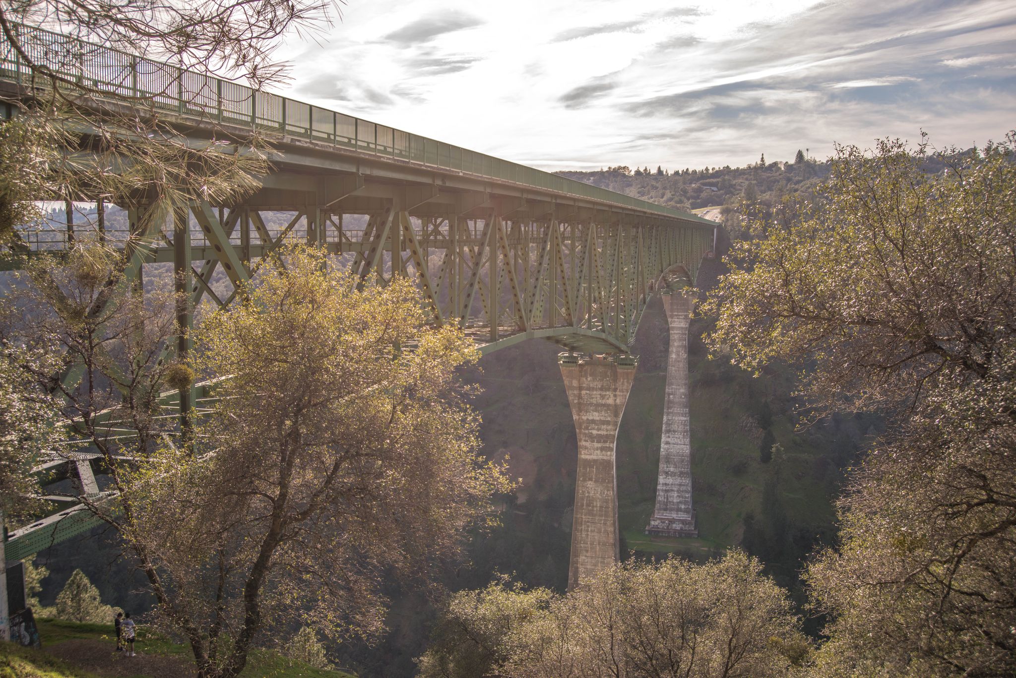 A large green truss bridge spans a deep, tree-filled valley on a bright day. - Confluence and Clementine Trail Loop