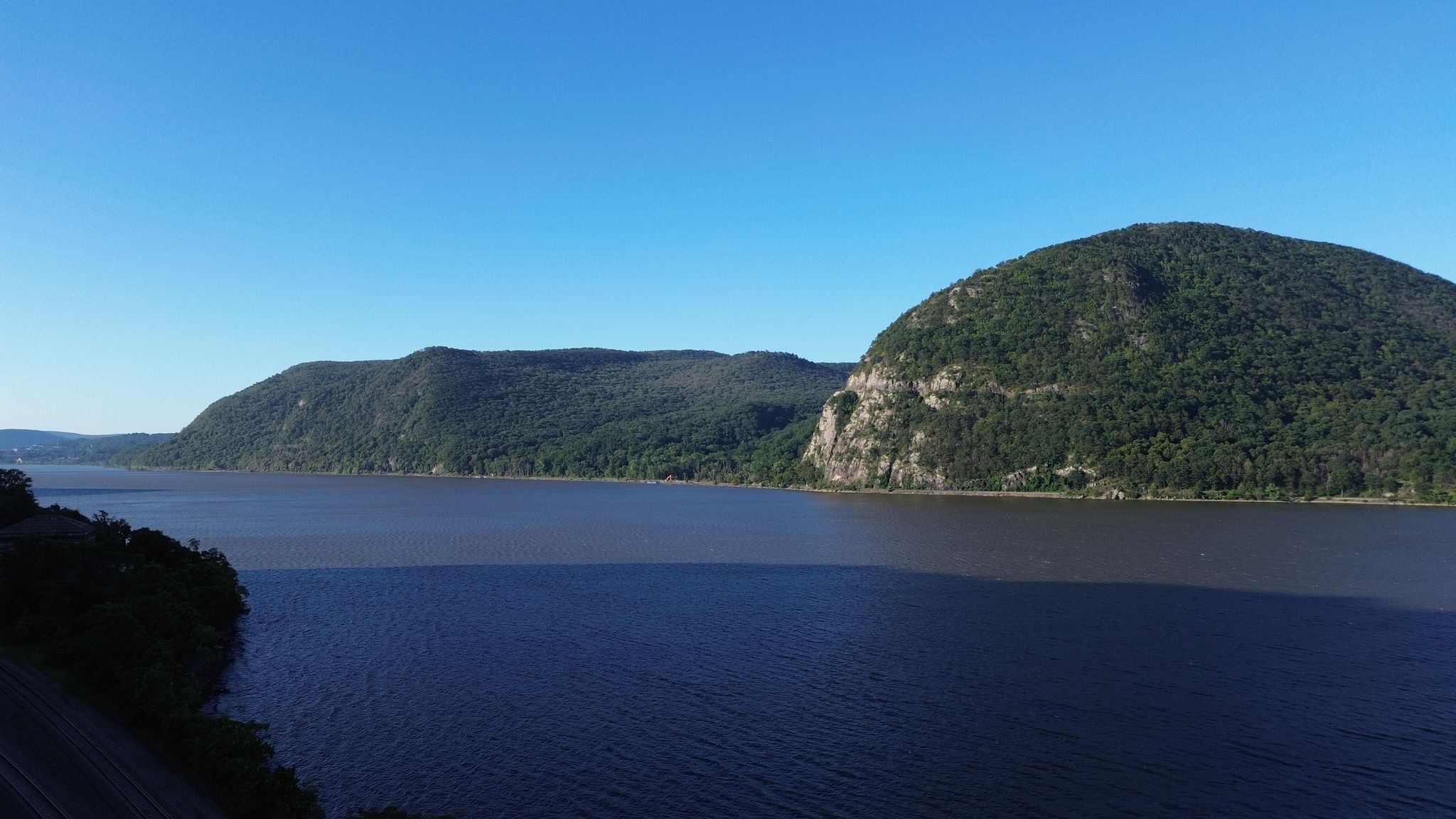 Wide river flowing between steep, forested mountains under a clear blue sky. - Sphagnum Pond – Black Rock Forest loop from Black Rock Forest
