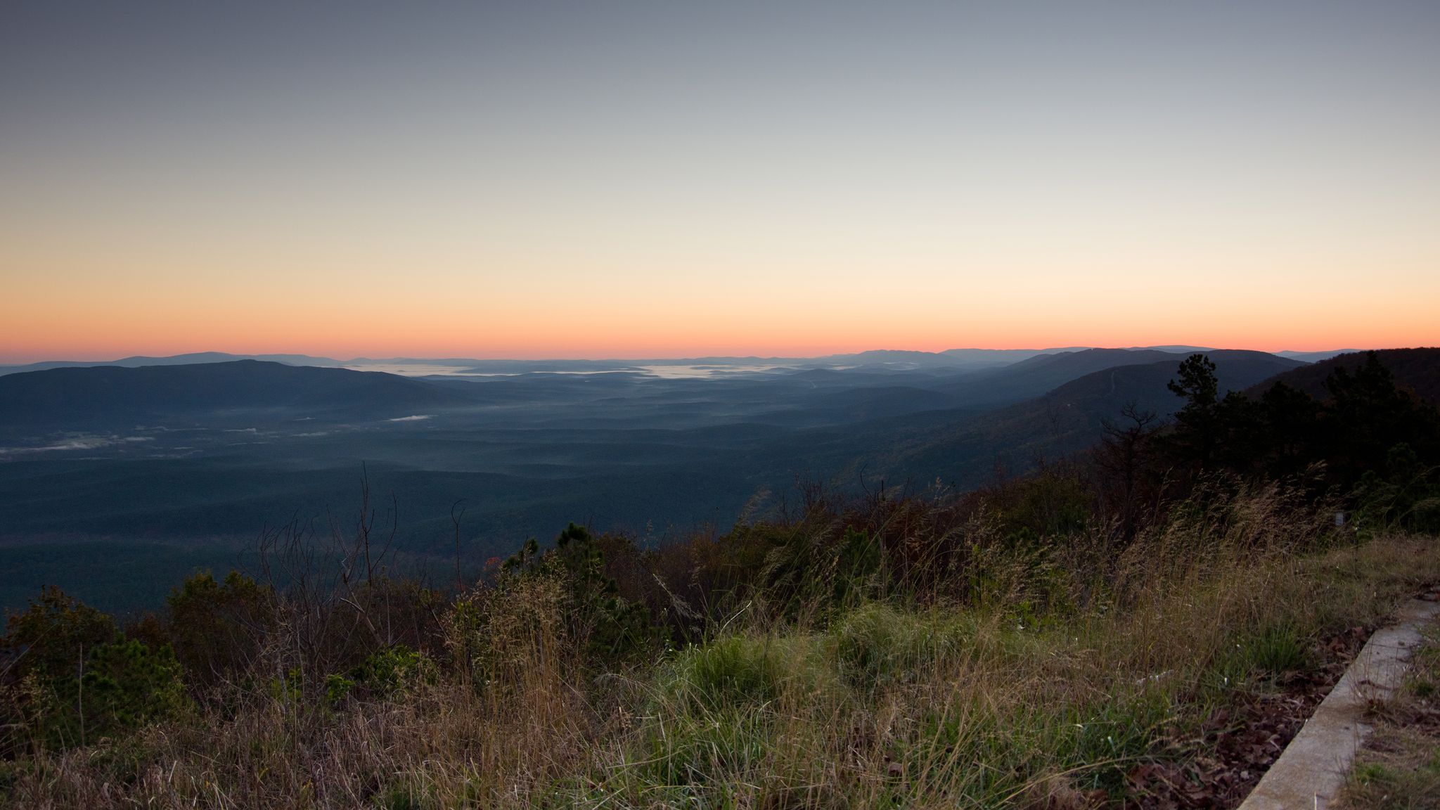 Panoramic view of misty valleys and rolling mountains under a colorful dawn sky. - Boardstand-Old Military Road Loop