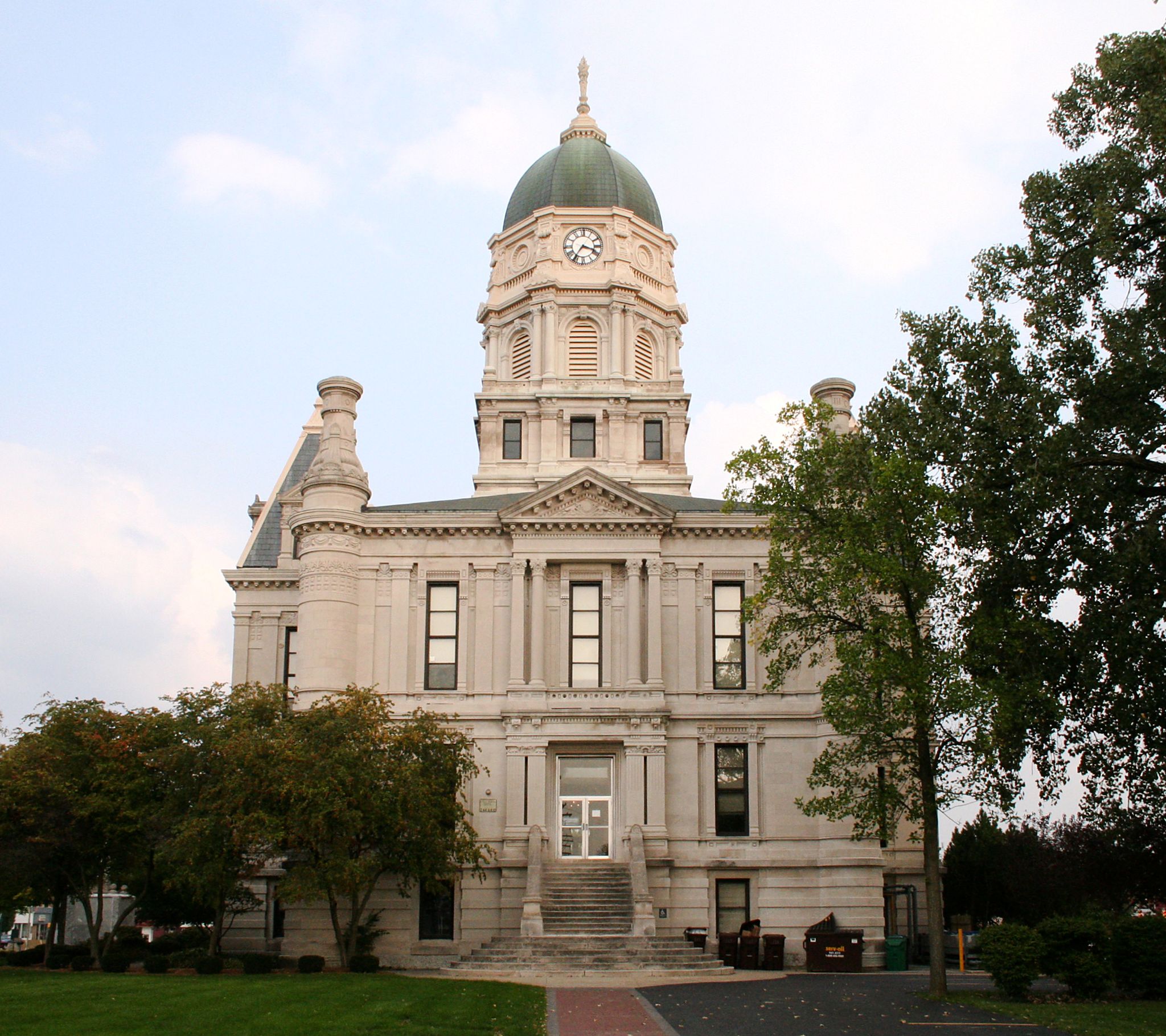 Ornate building with green dome and clock tower, surrounded by trees and grass. - Fort Wayne to Warsaw