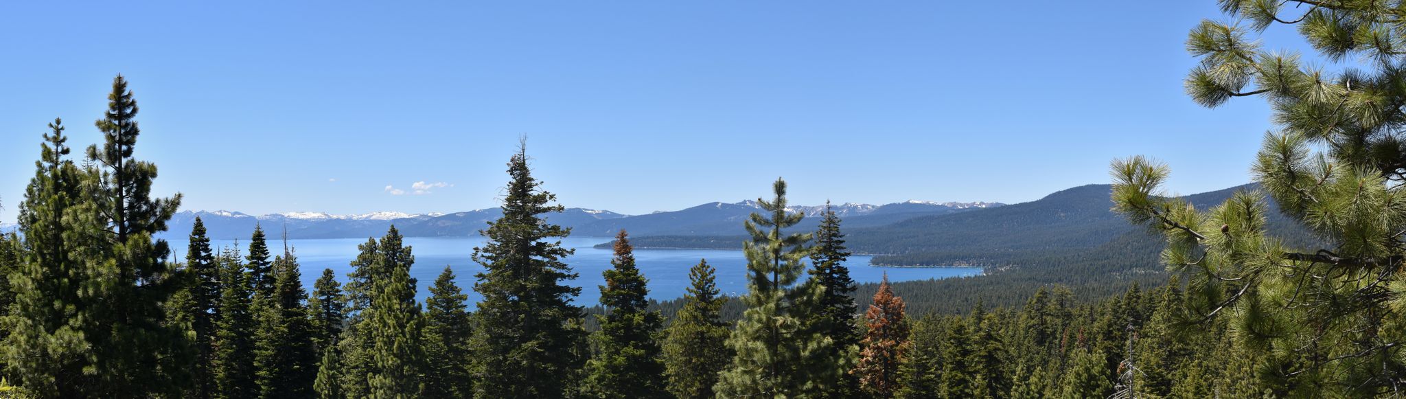 Panoramic view of a blue lake, pine forests, and distant snow-capped mountains. - Kings Beach to Beaver Tail Trail loop