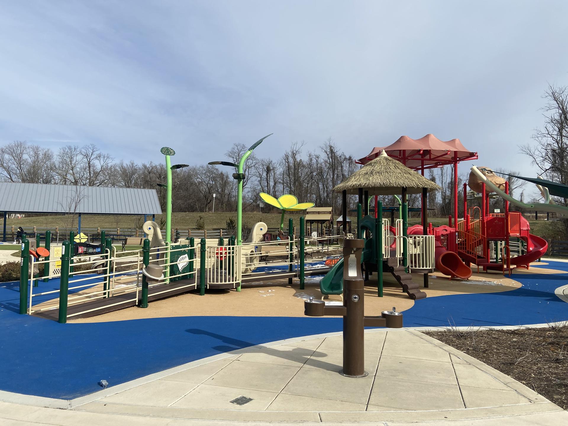 A colorful, accessible playground with slides and ramps under a bright sky.