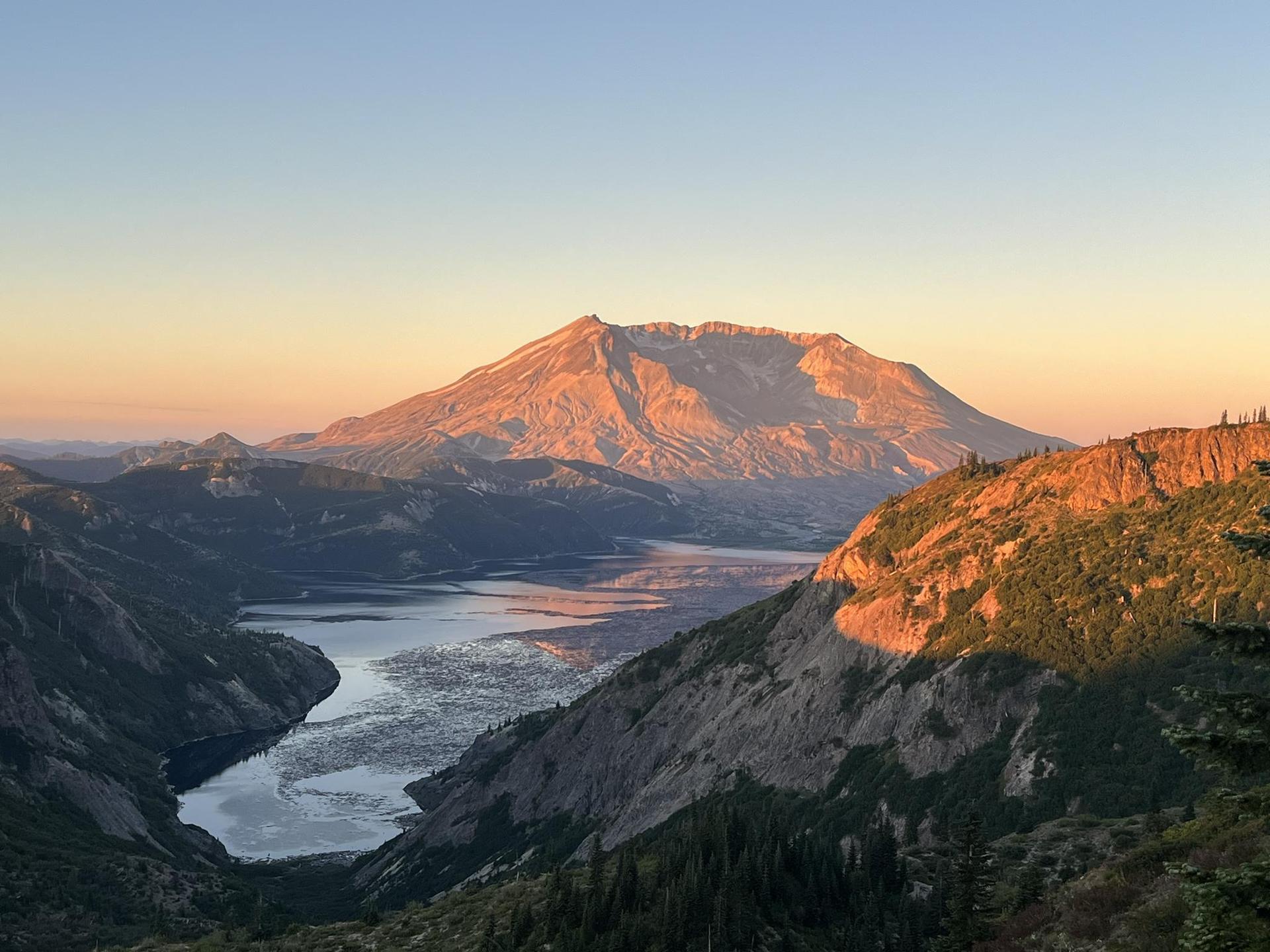 Majestic mountain and lake in a valley, bathed in golden hour light.