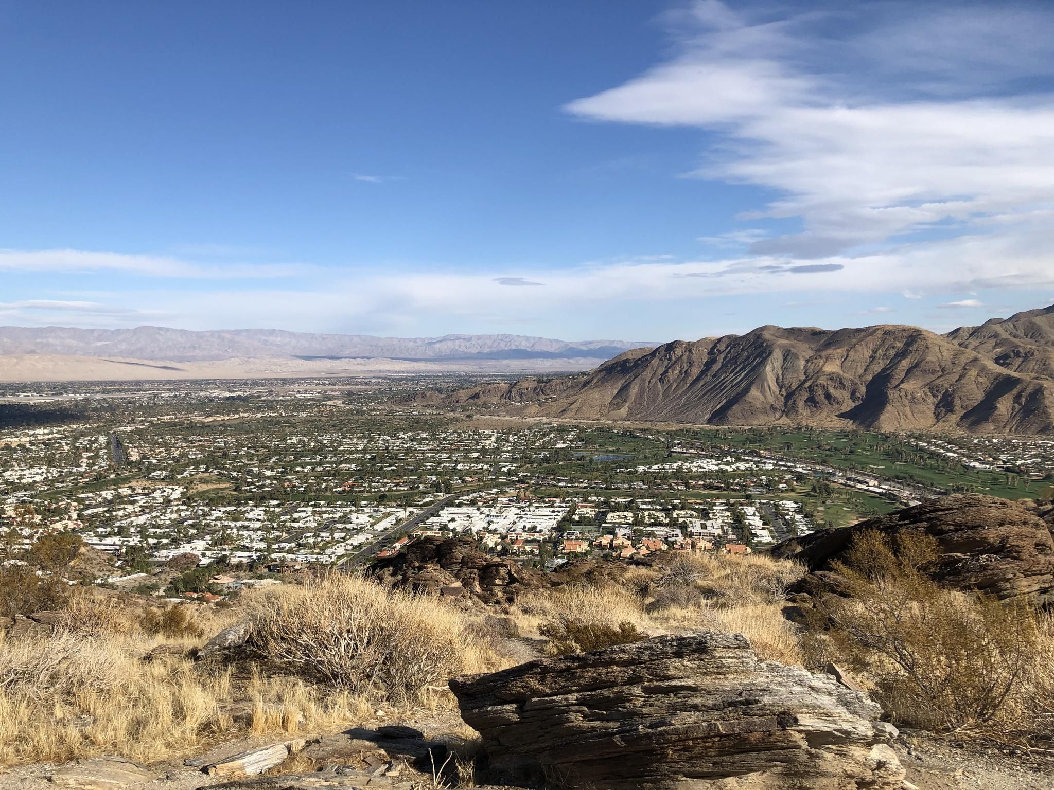 Expansive desert valley with a town, green areas, and rugged mountains under blue sky. - South Lykken Trail Loop
