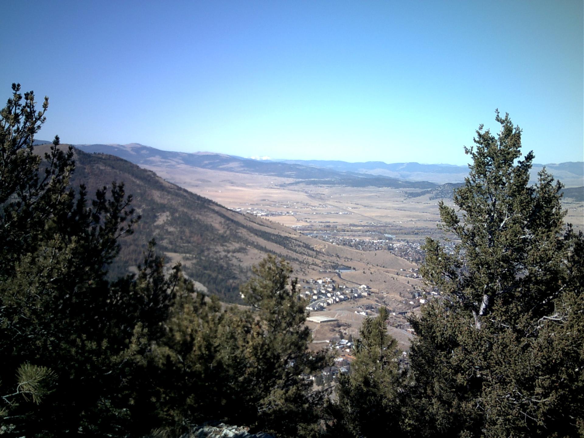 Panoramic view of a dry valley town nestled between mountains under clear skies.