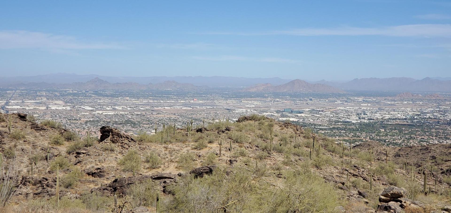 Panoramic view of a sprawling city from a desert hill on a clear day.