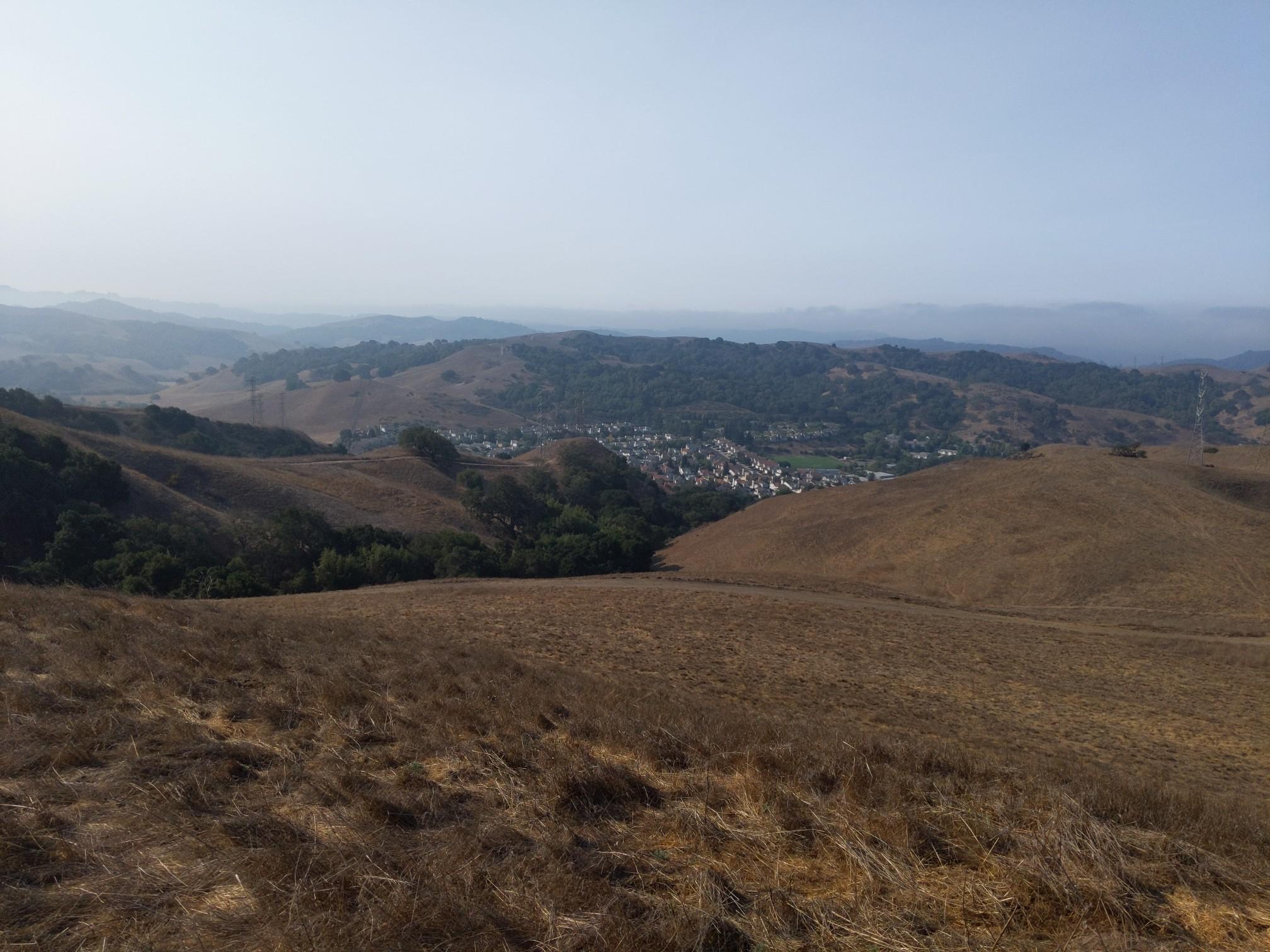 Expansive view of dry, rolling hills with a small town nestled in the valley.