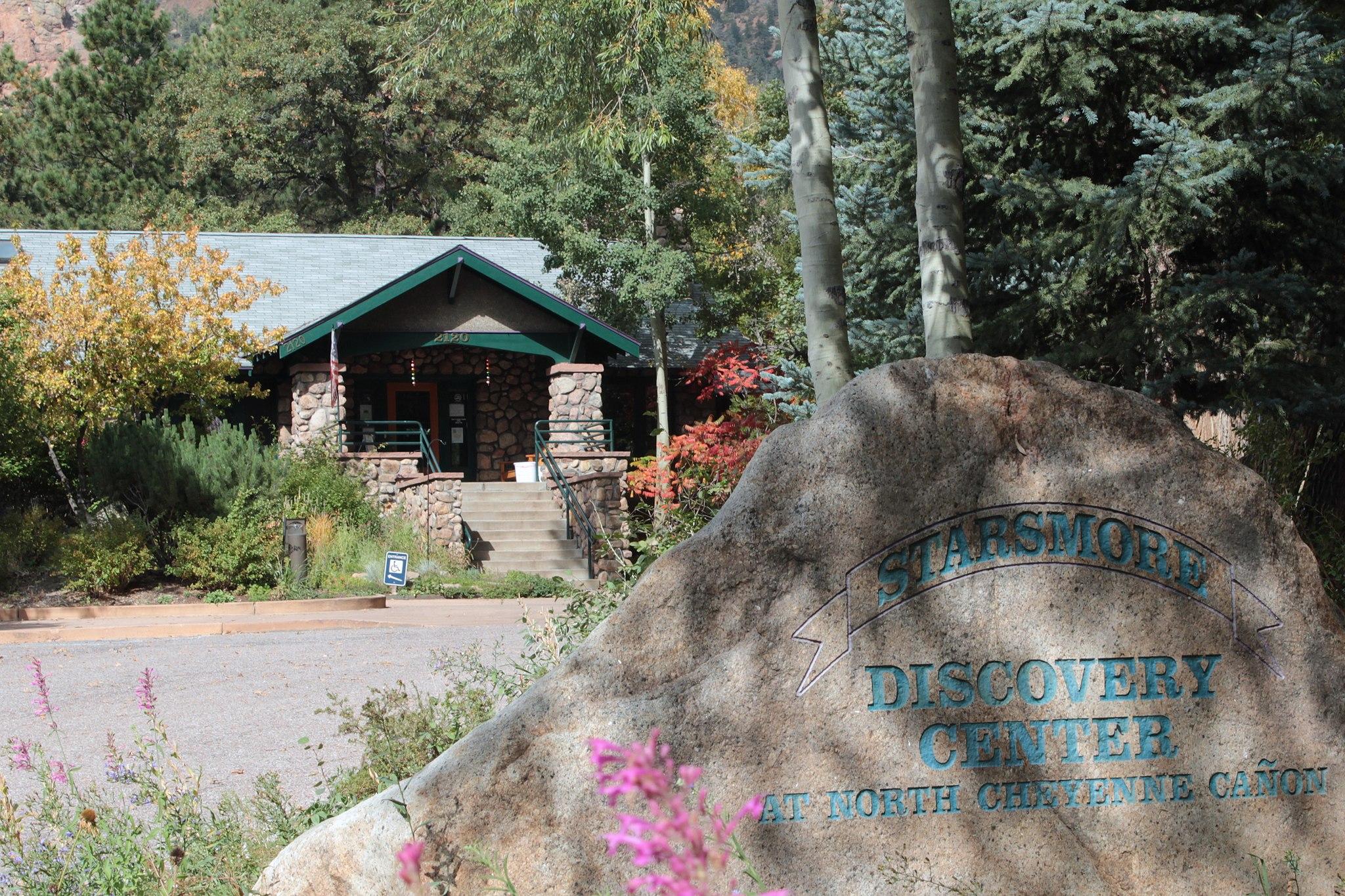 A large stone sign in front of a rustic building surrounded by trees.