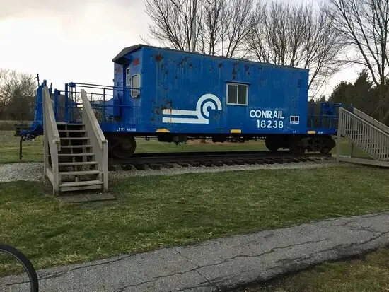 An old blue train caboose on tracks, with wooden stairs.